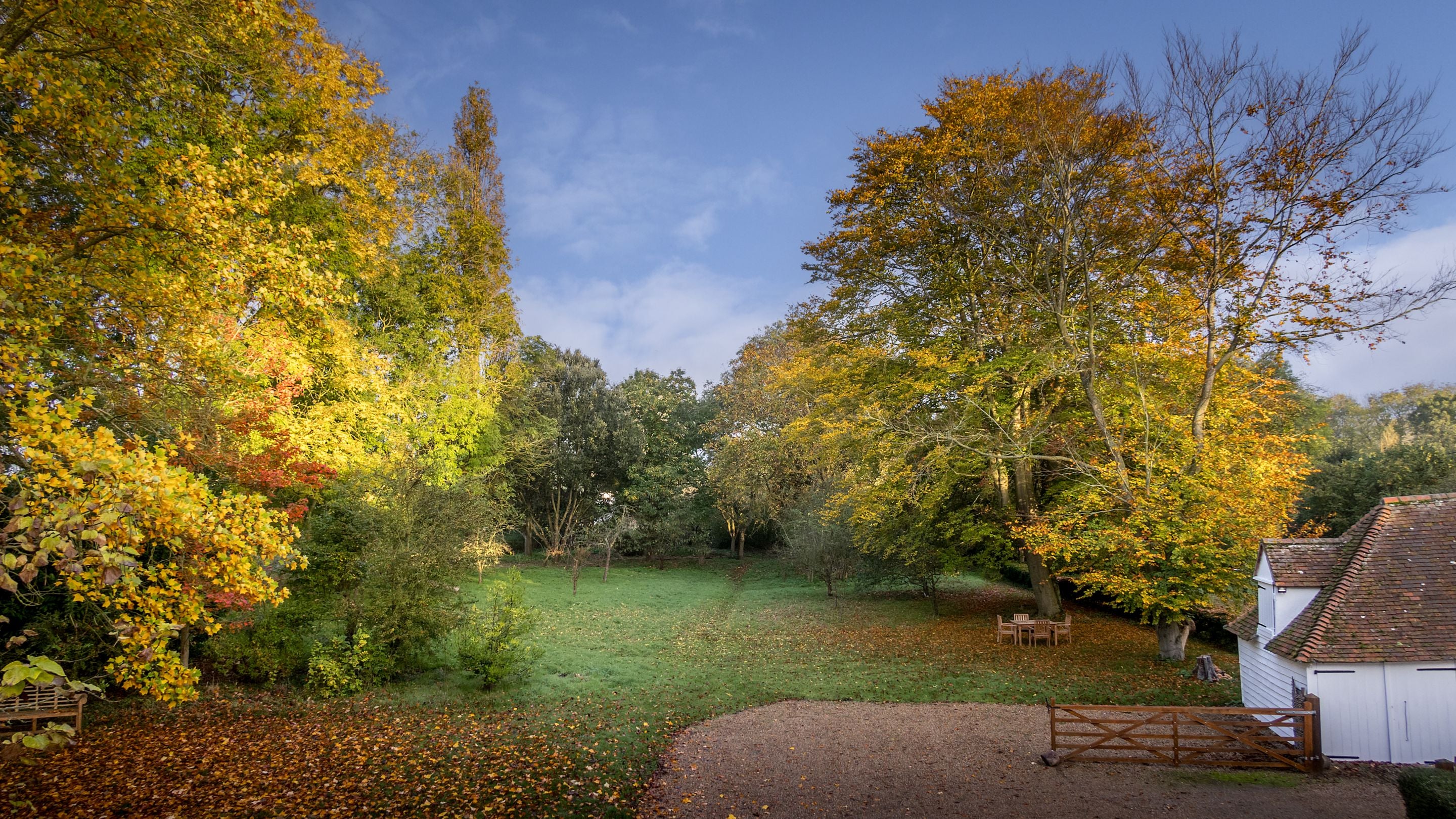 An aerial view of the garden at Thorington Hall in autumn, with large lawn area and trees, Suffolk
