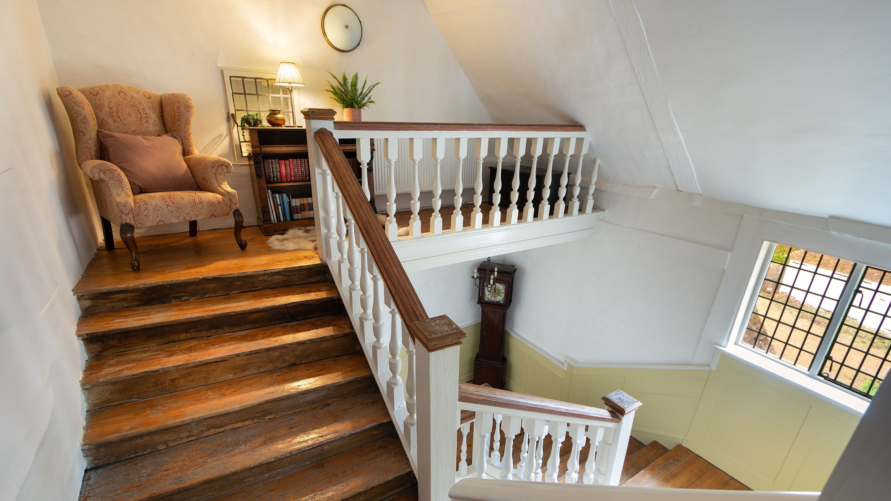 The top of the east staircase at Thorington Hall, with armchair and bookcase on the landing, Suffolk
