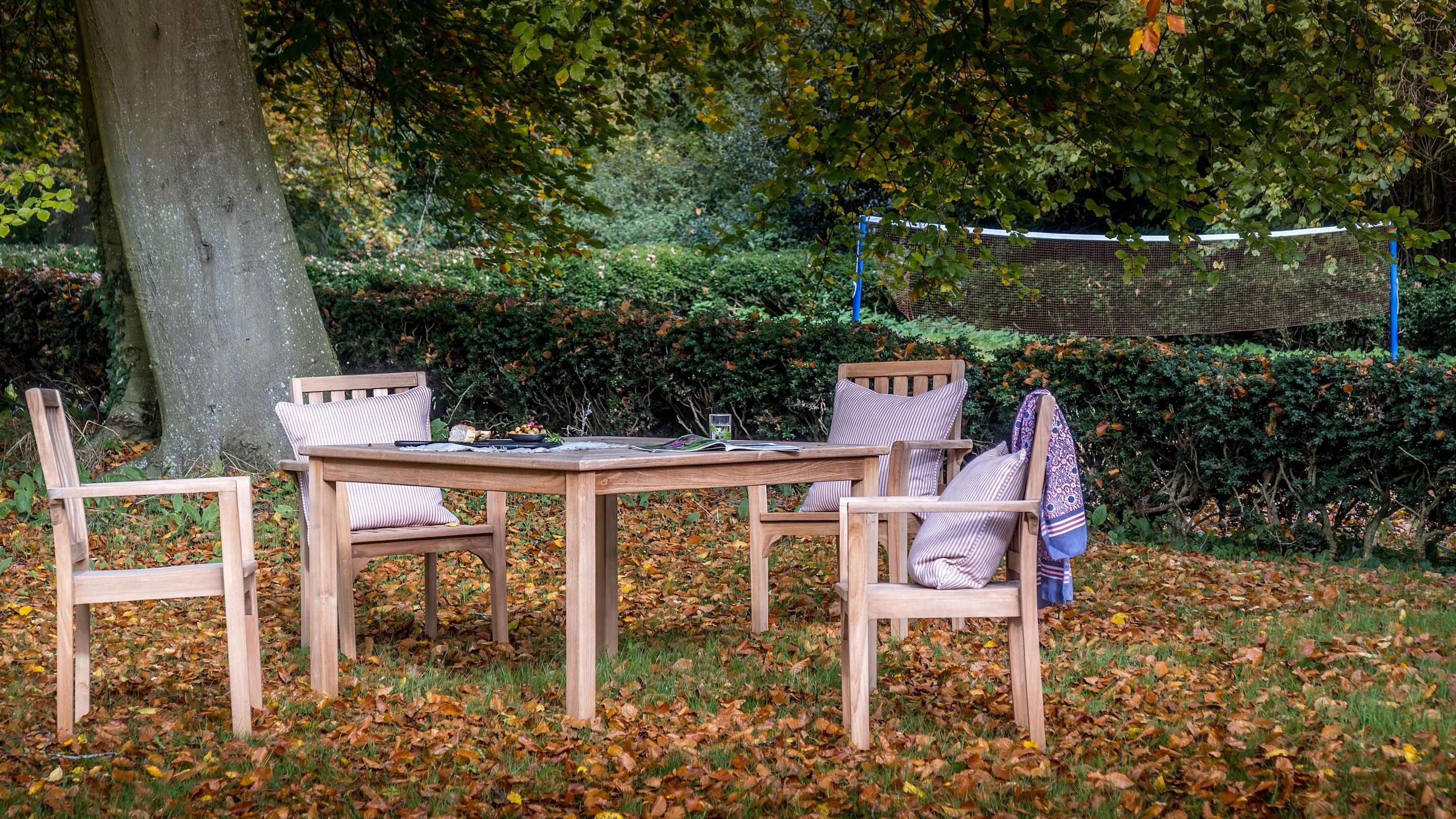Outdoor dining furniture in the garden of Thorington Hall, with the badminton area in the background, Suffolk