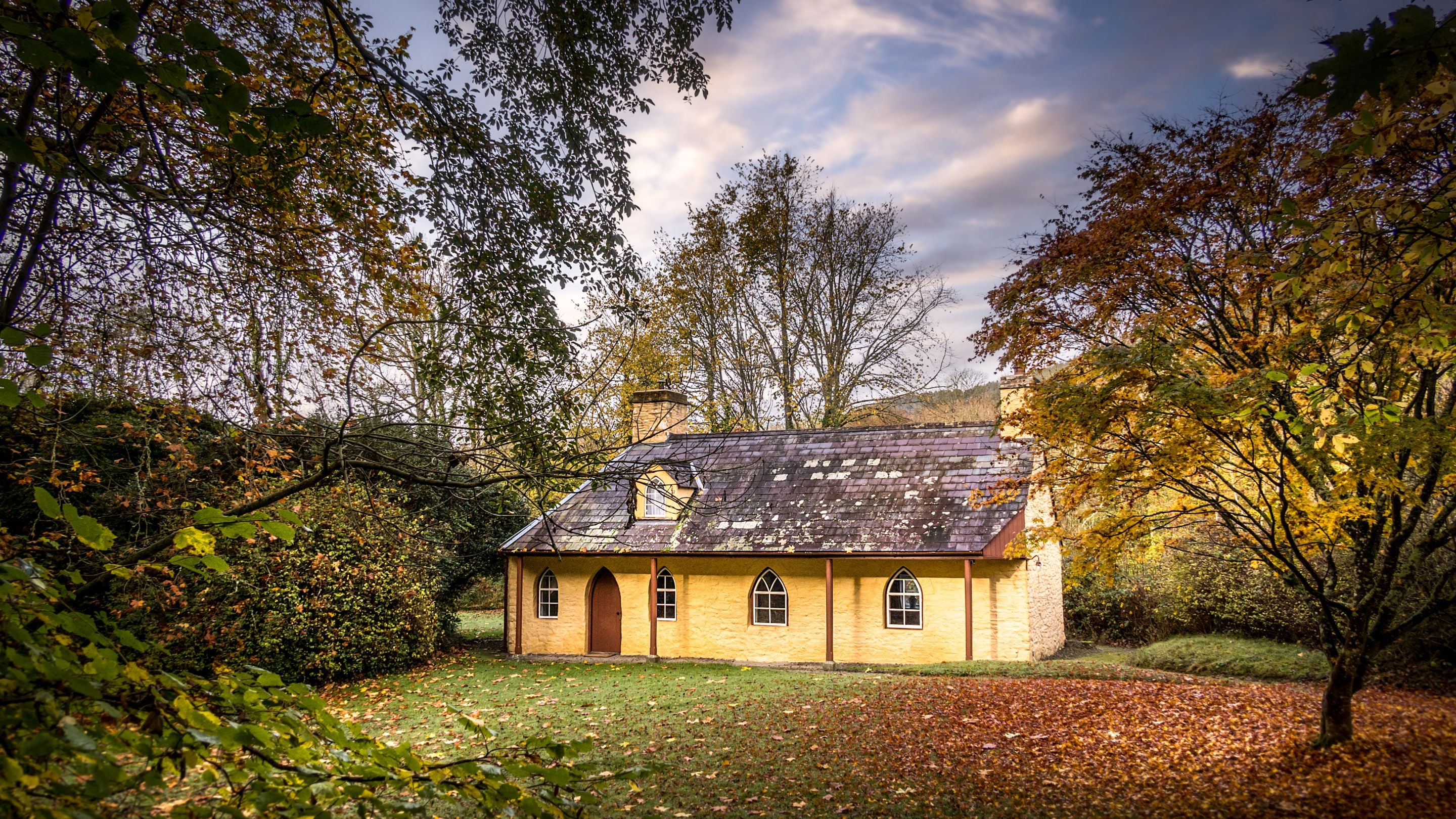 The exterior of Abermydyr, surrounded by trees and lawned garden, Ceredigion