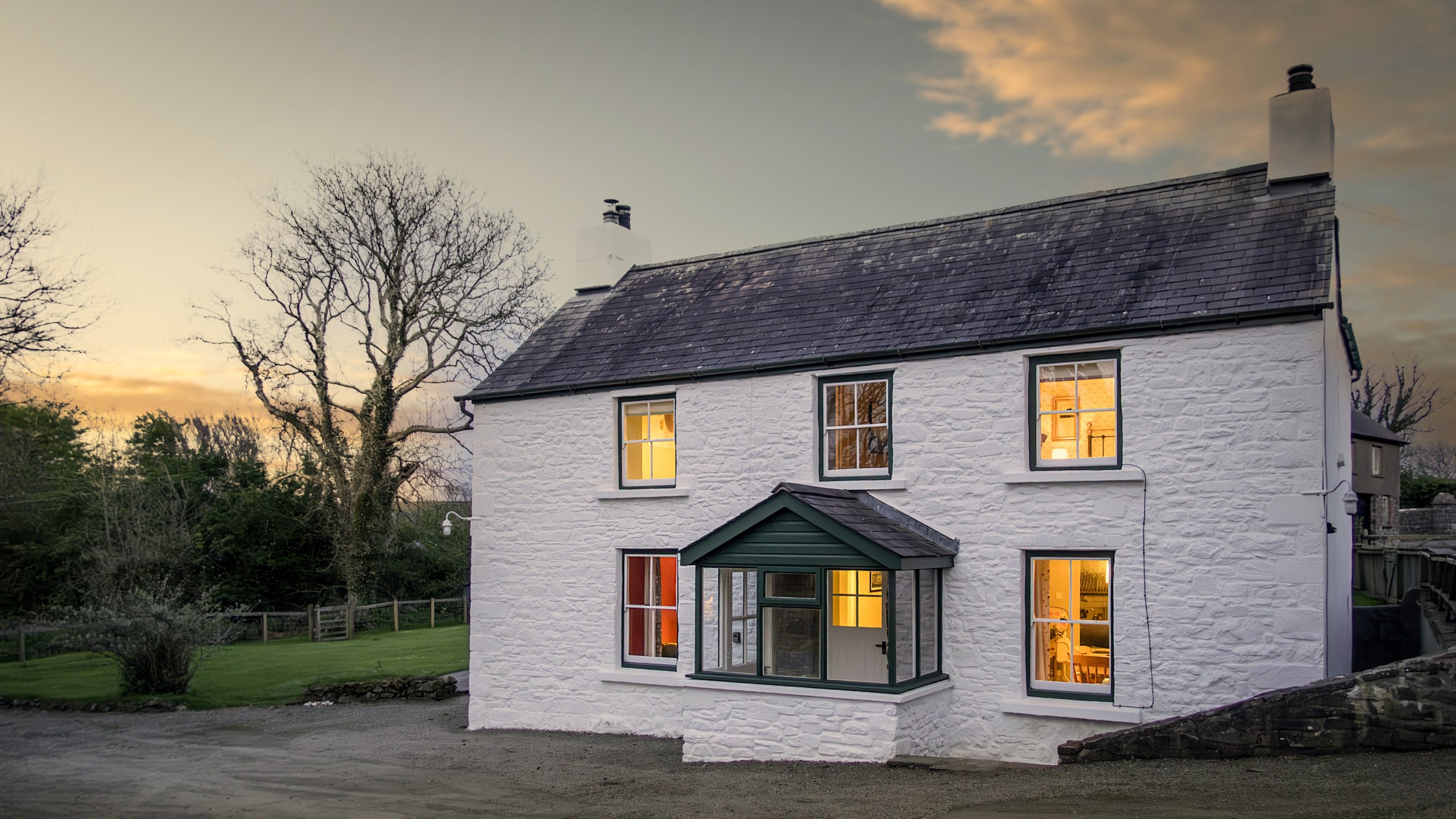 The exterior of Caerllan in the evening, with lights coming from the windows, Ceredigion