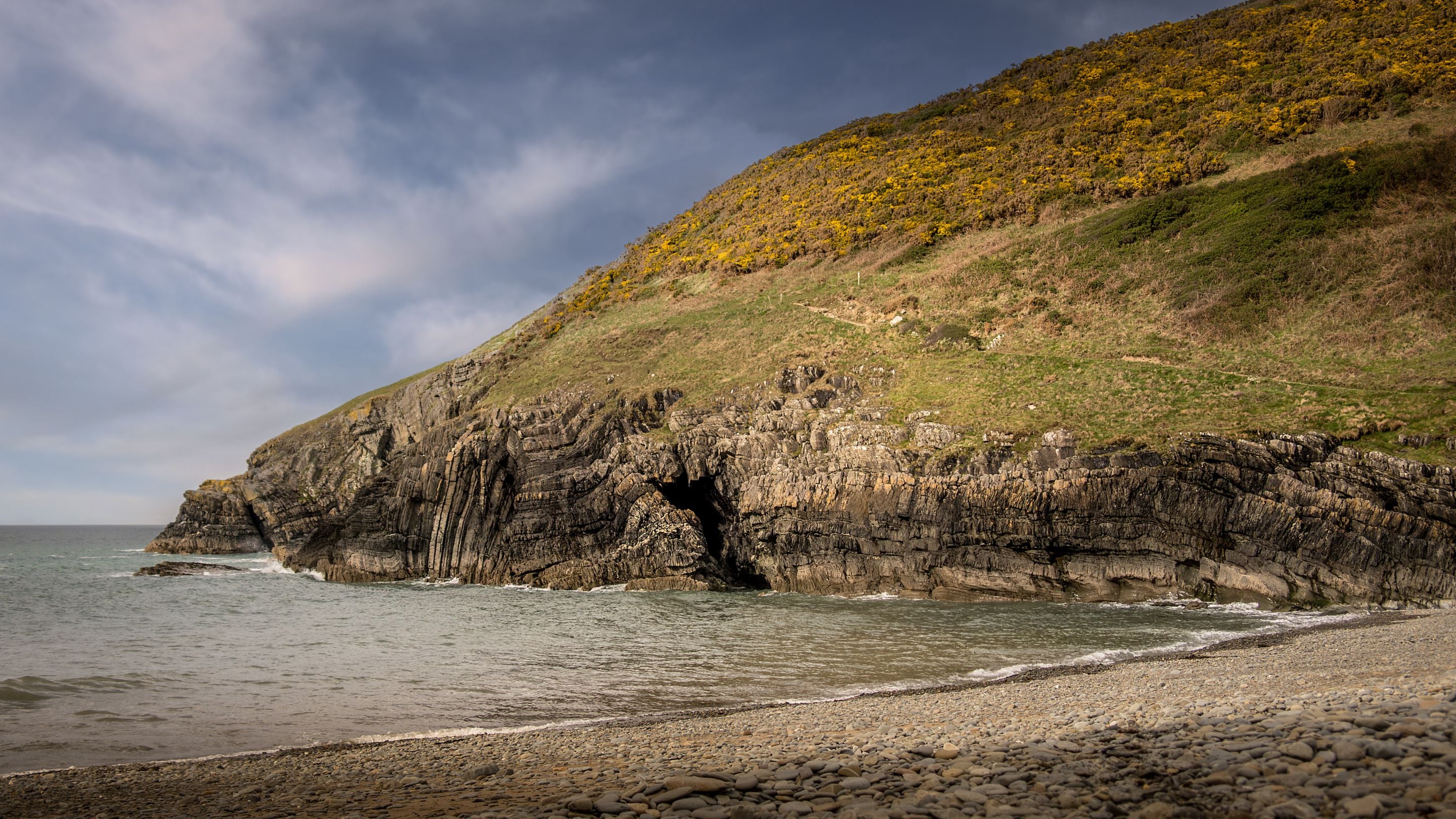 The cliffside and pebble beach at Cwmtydu Cove near Caerllan, Ceredigion