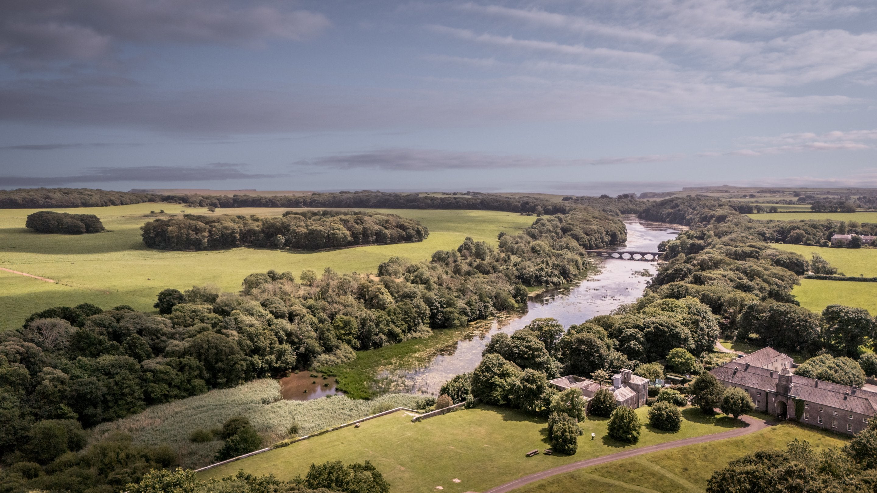 An aerial view of Cawdor in the treeline along the edge of the lakes at the Stackpole Estate, Pembrokeshire
