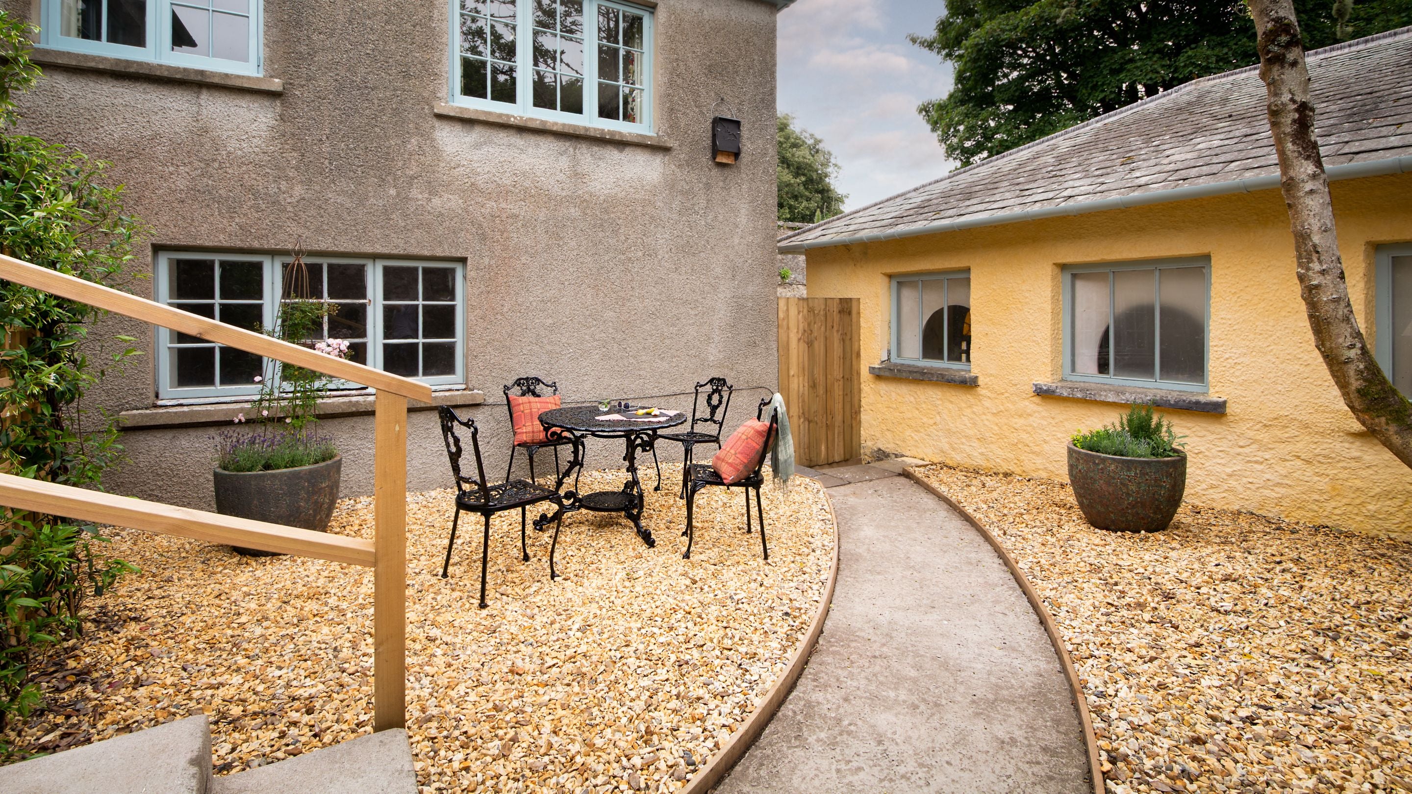 Cawdor's courtyard garden, with outdoor table and chairs, path, gravelled areas and potted plants, Pembrokeshire