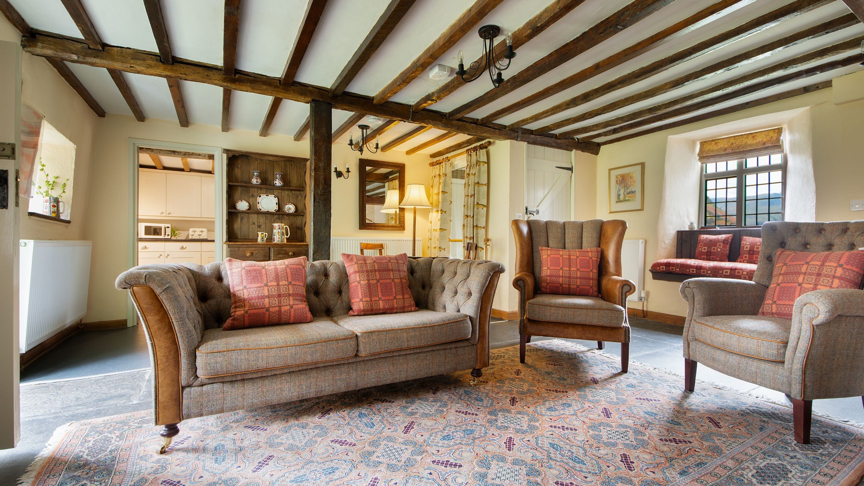The sitting room with wood beams, sofas, armchairs and window seats at Fron Dirion, Powys