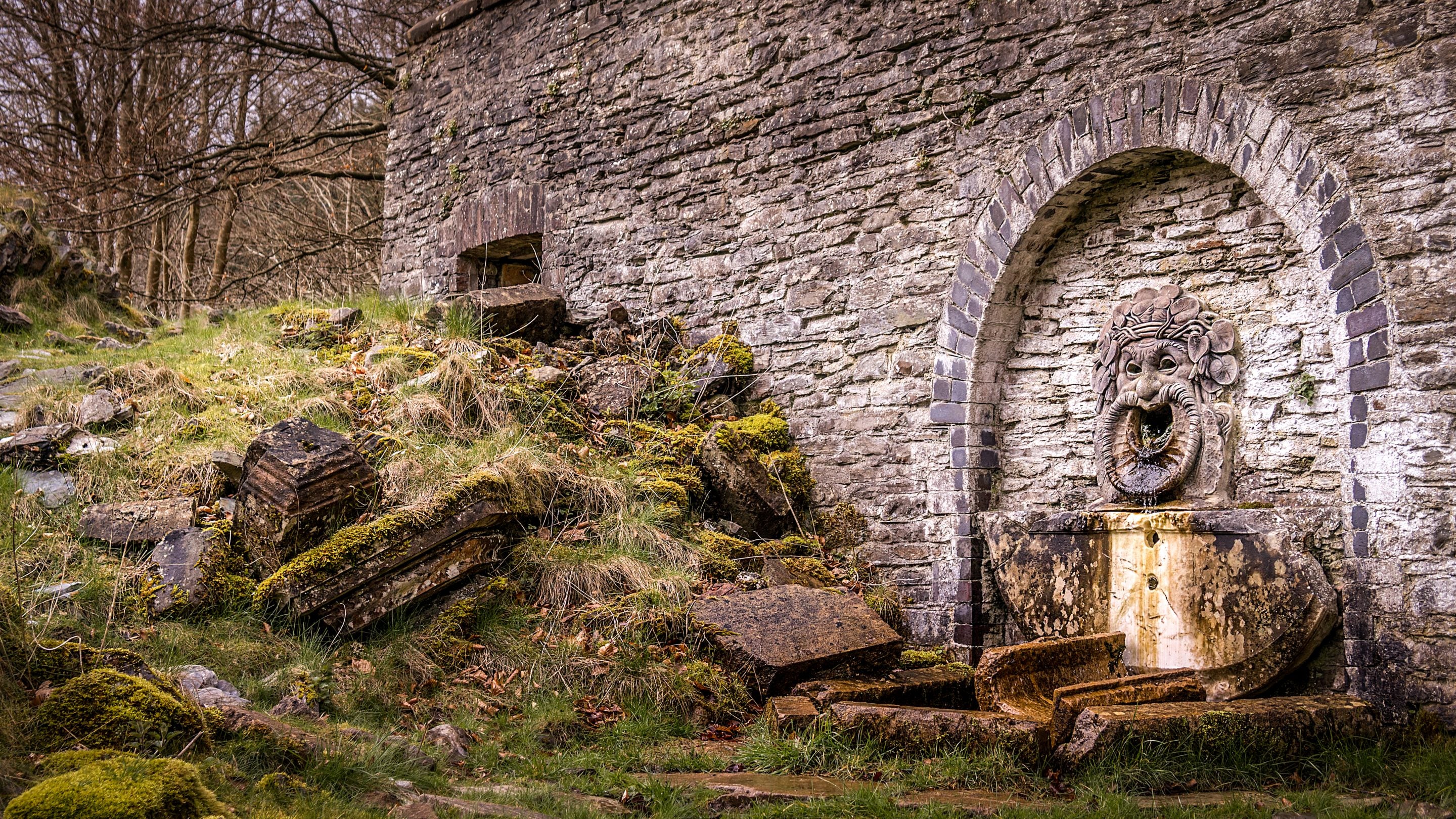 The Silenus Fountain, a male face carved in stone, where water falls from the open mouth. It is in the Hafod Estate, near Hawthorn Cottage, Ceredigion