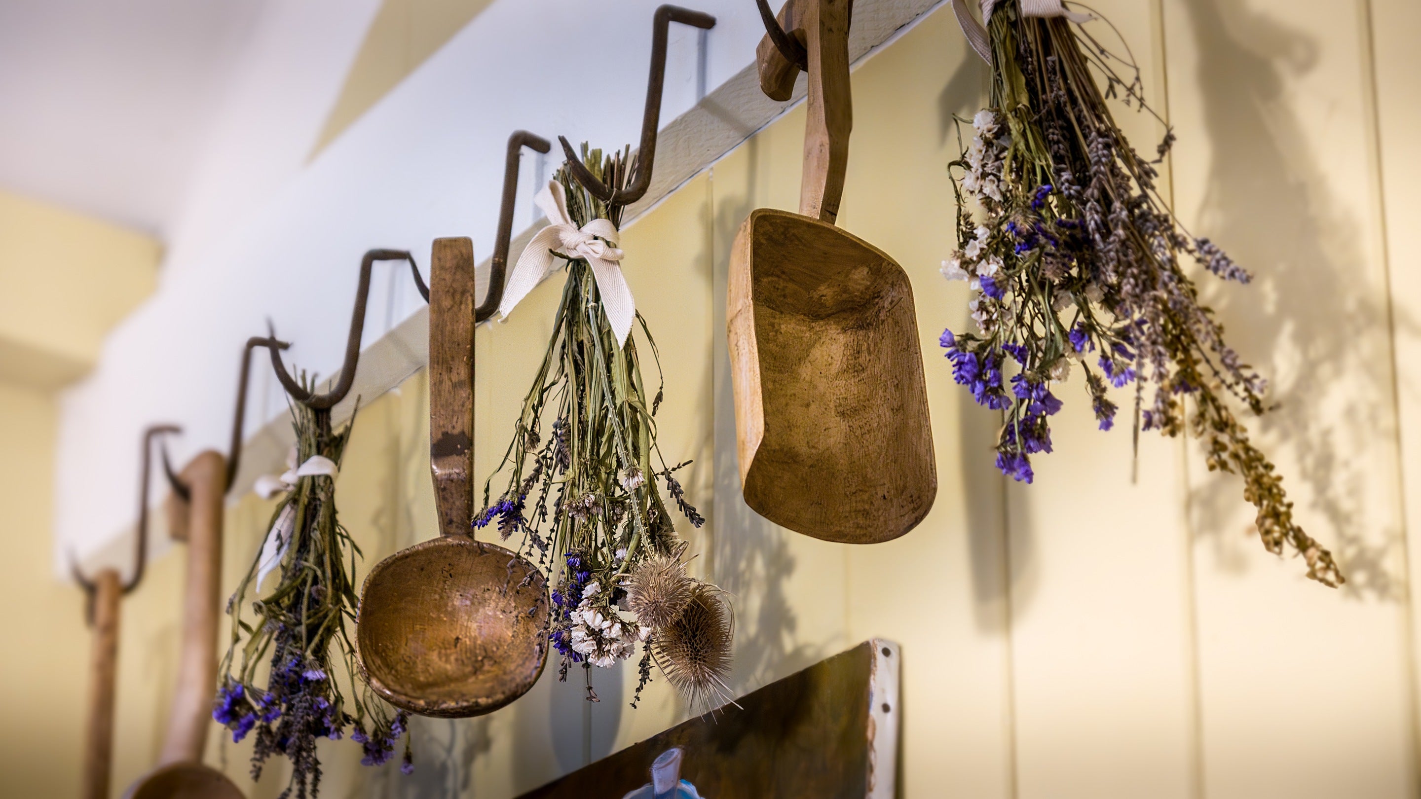 Original meat hooks in the kitchen at Hawthorn Cottage are decorated with Welsh spoons and dried flowers, Ceredigion