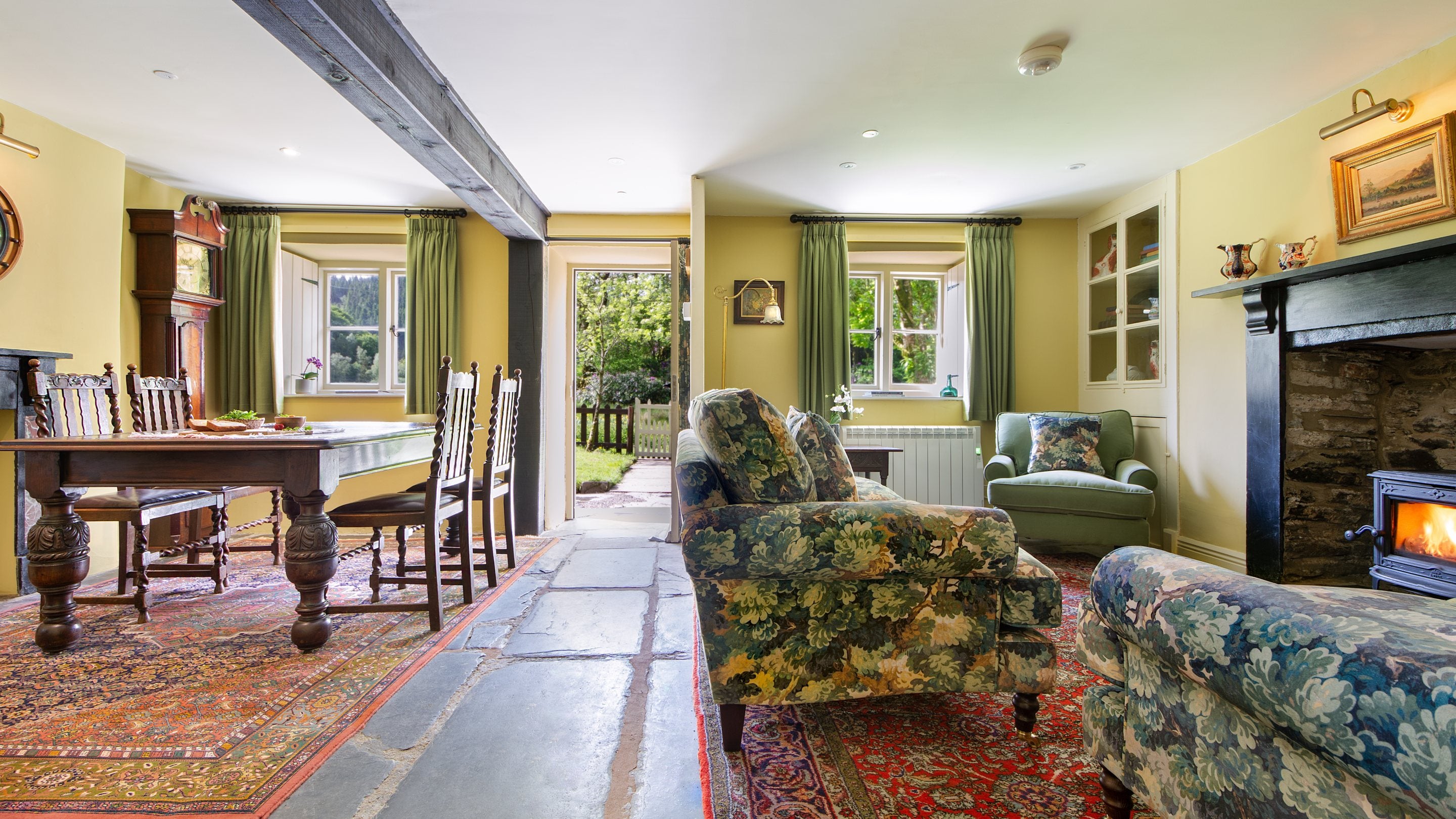 The sitting and dining room with original slate floor and woodburner in the original inglenook at Hawthorn Cottage, Ceredigion