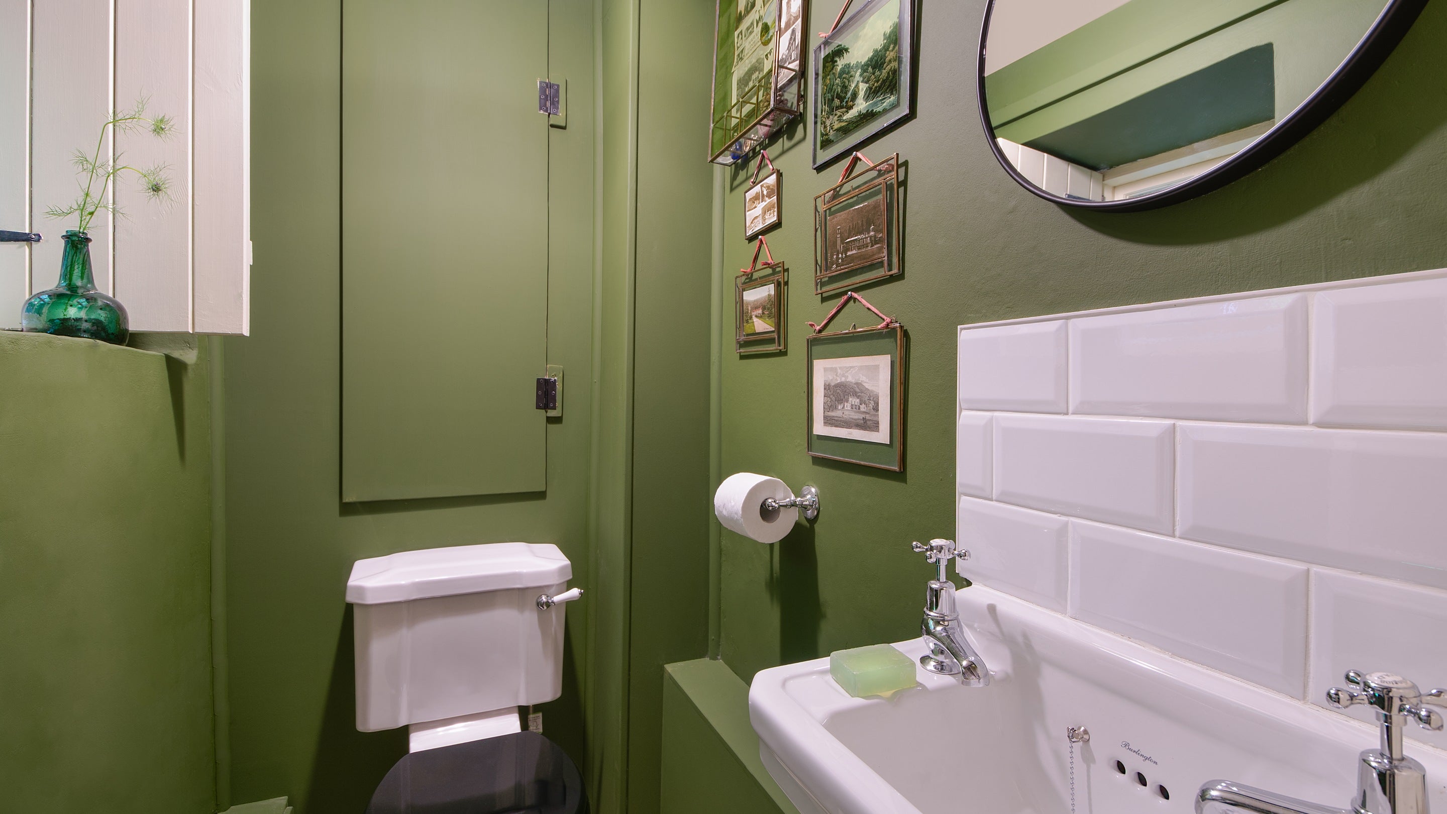 The ground floor toilet at Hawthorn Cottage, with a gallery wall with images and art of the Hafod estate, including the old house, Ceredigion