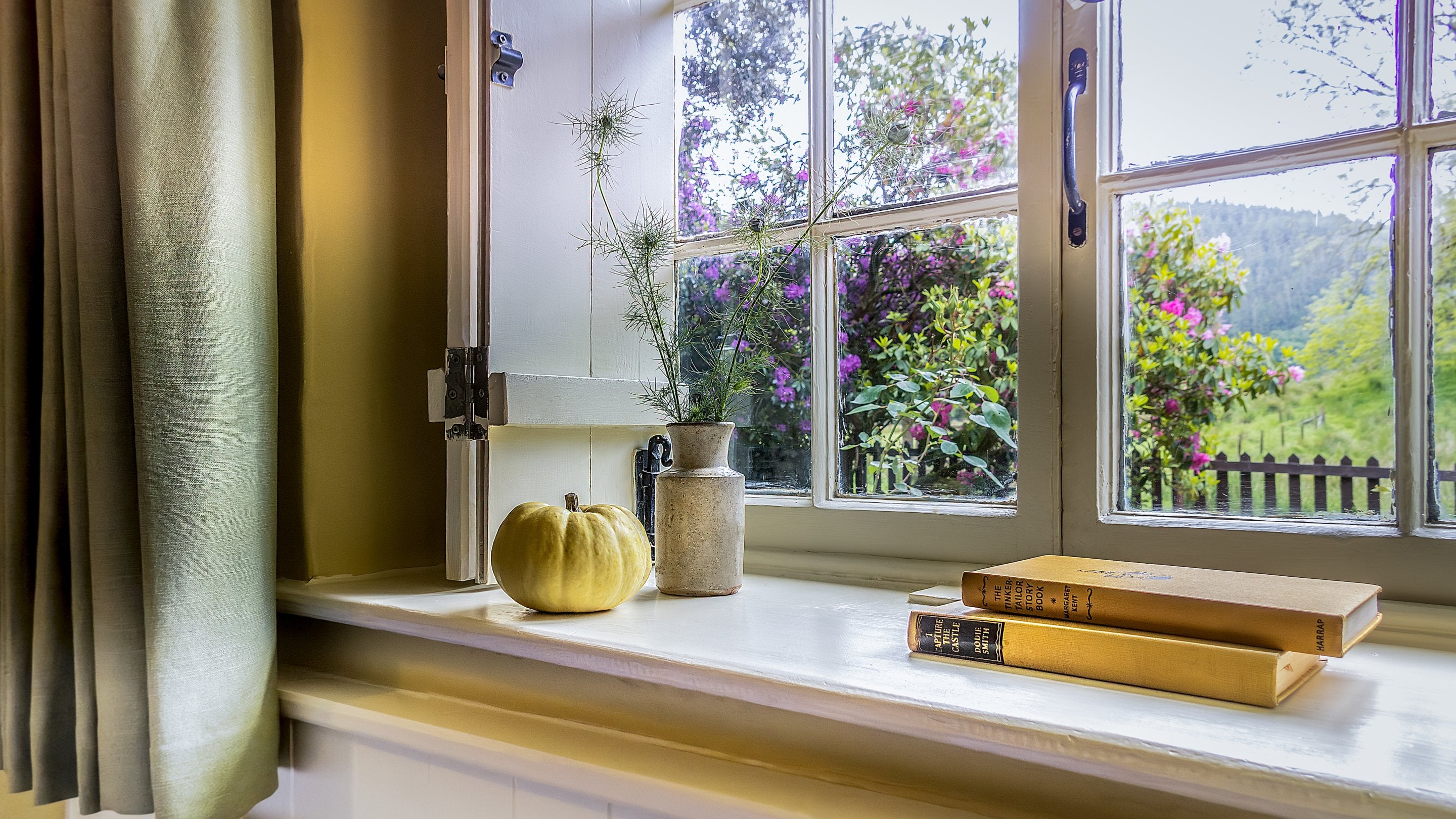 The ground floor bedroom window at Hawthorn Cottage, with restored shutters and views of the garden and Hafod Estate beyond, Ceredigion