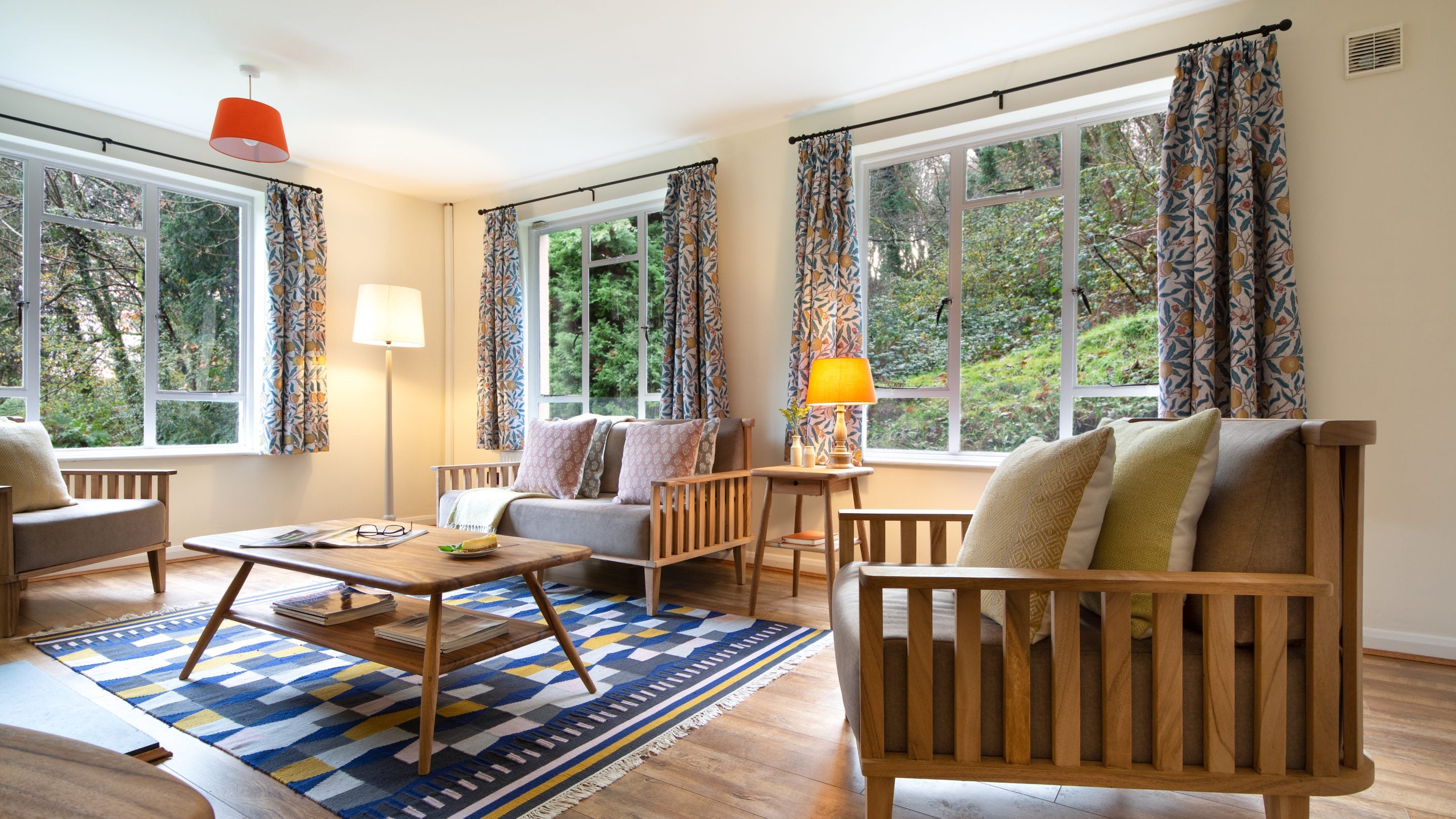 The bright and airy sitting room with three windows at Little Milford Lodge, Pembrokeshire