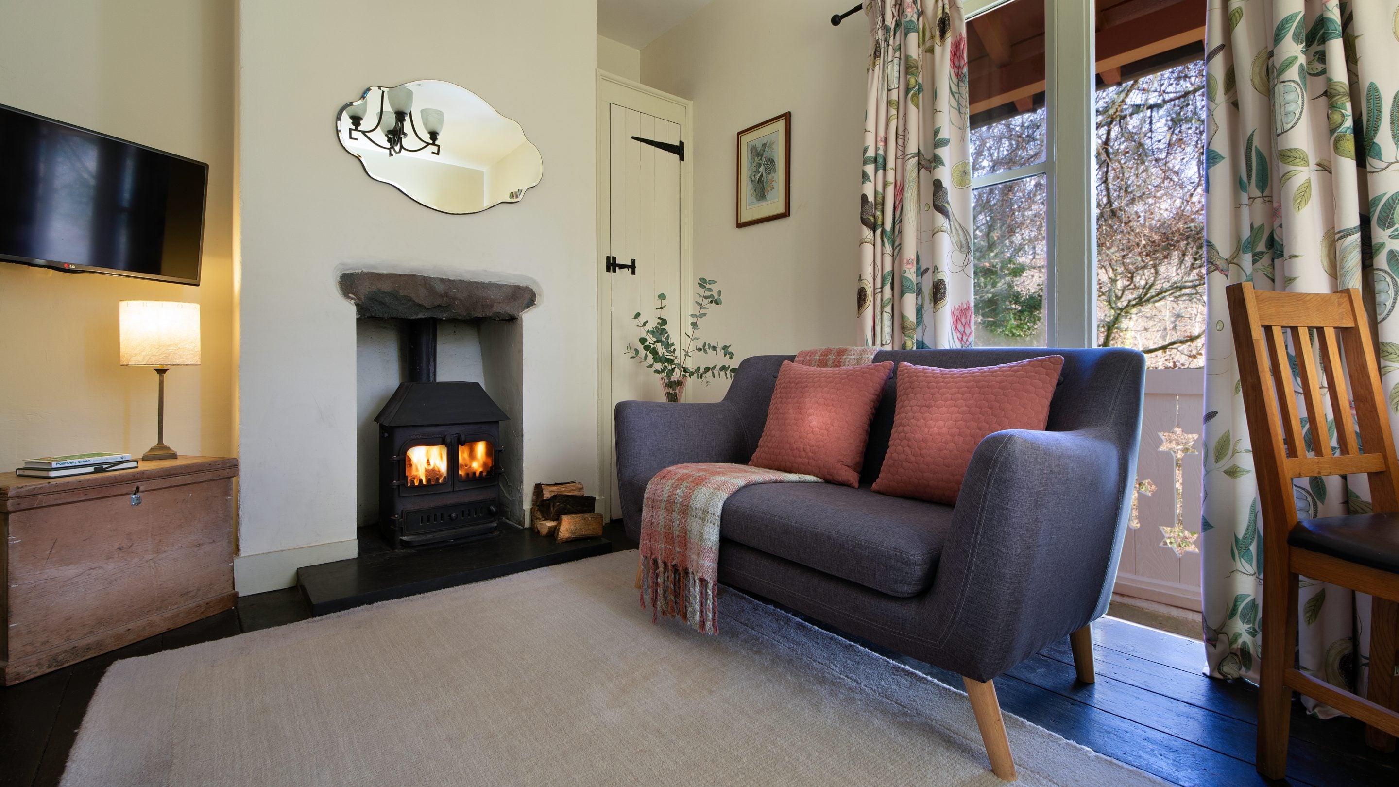 The sitting room with woodburning stove and glass doors onto the veranda at Nant Las, Gwynedd