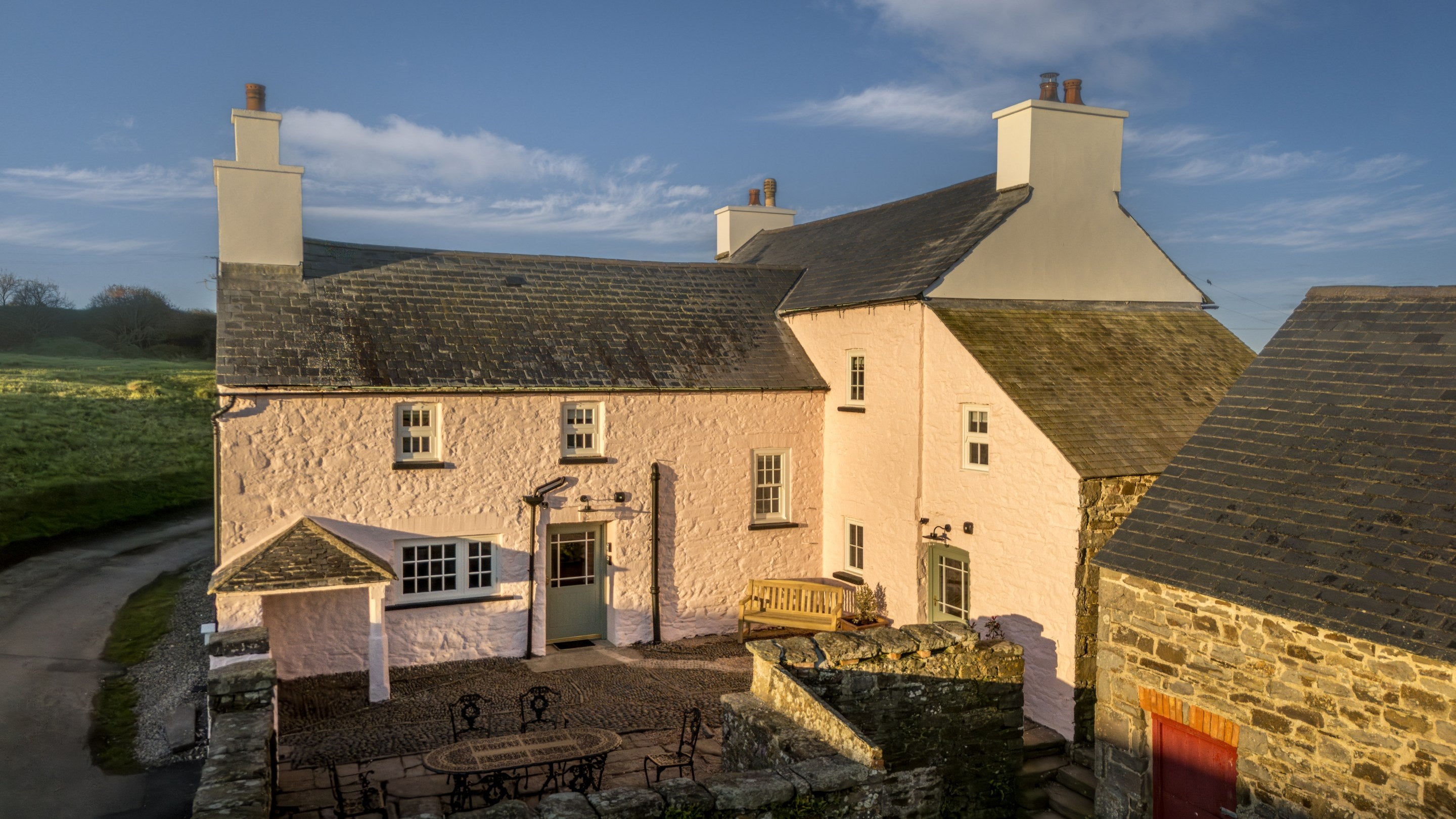 An aerial view of Newgale Wood Farm, a pink cottage with cobbled courtyard, Pembrokeshire