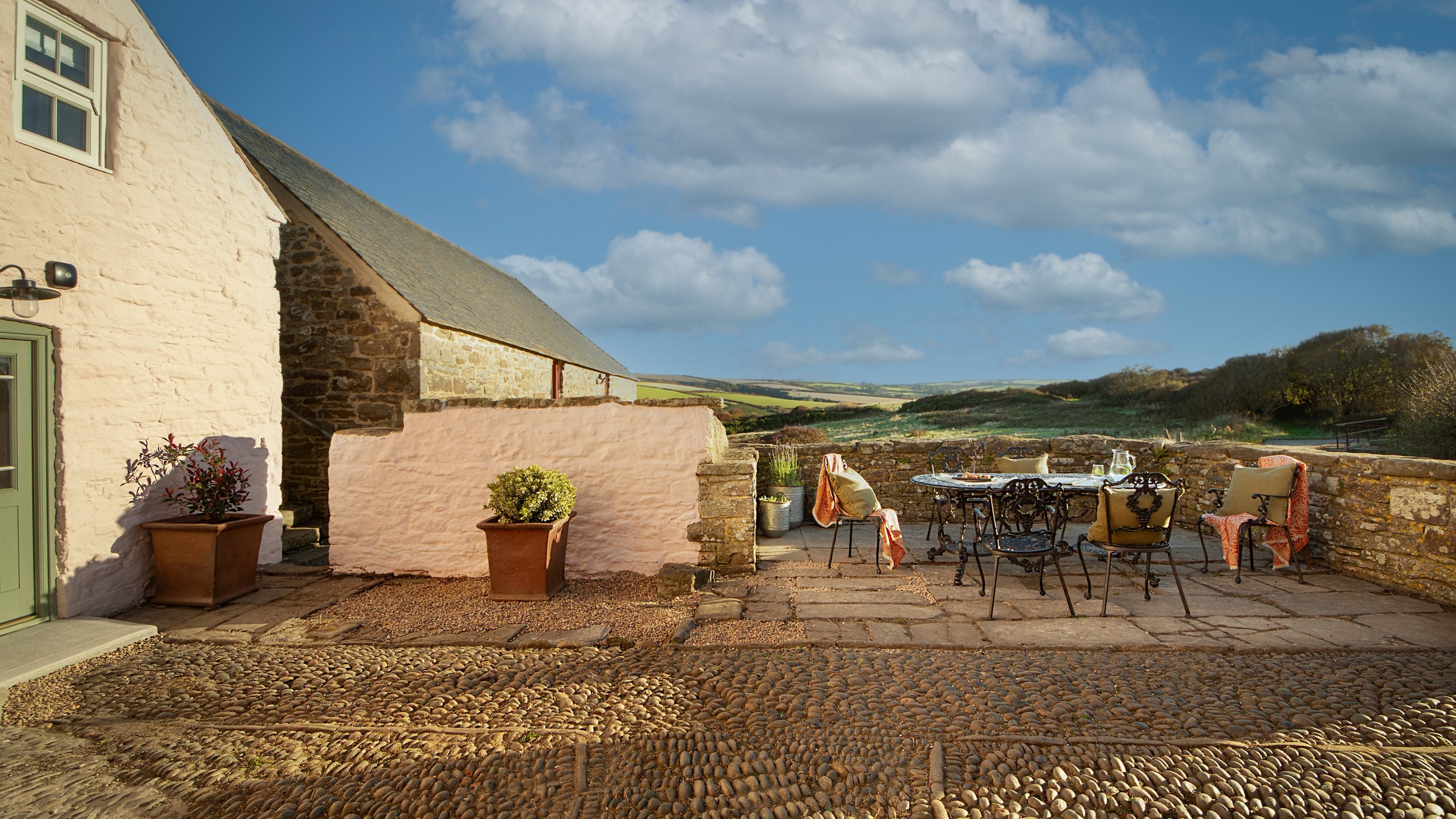 The courtyard with outdoor dining furniture and countryside views at Newgale Wood Farm, Pembrokeshire