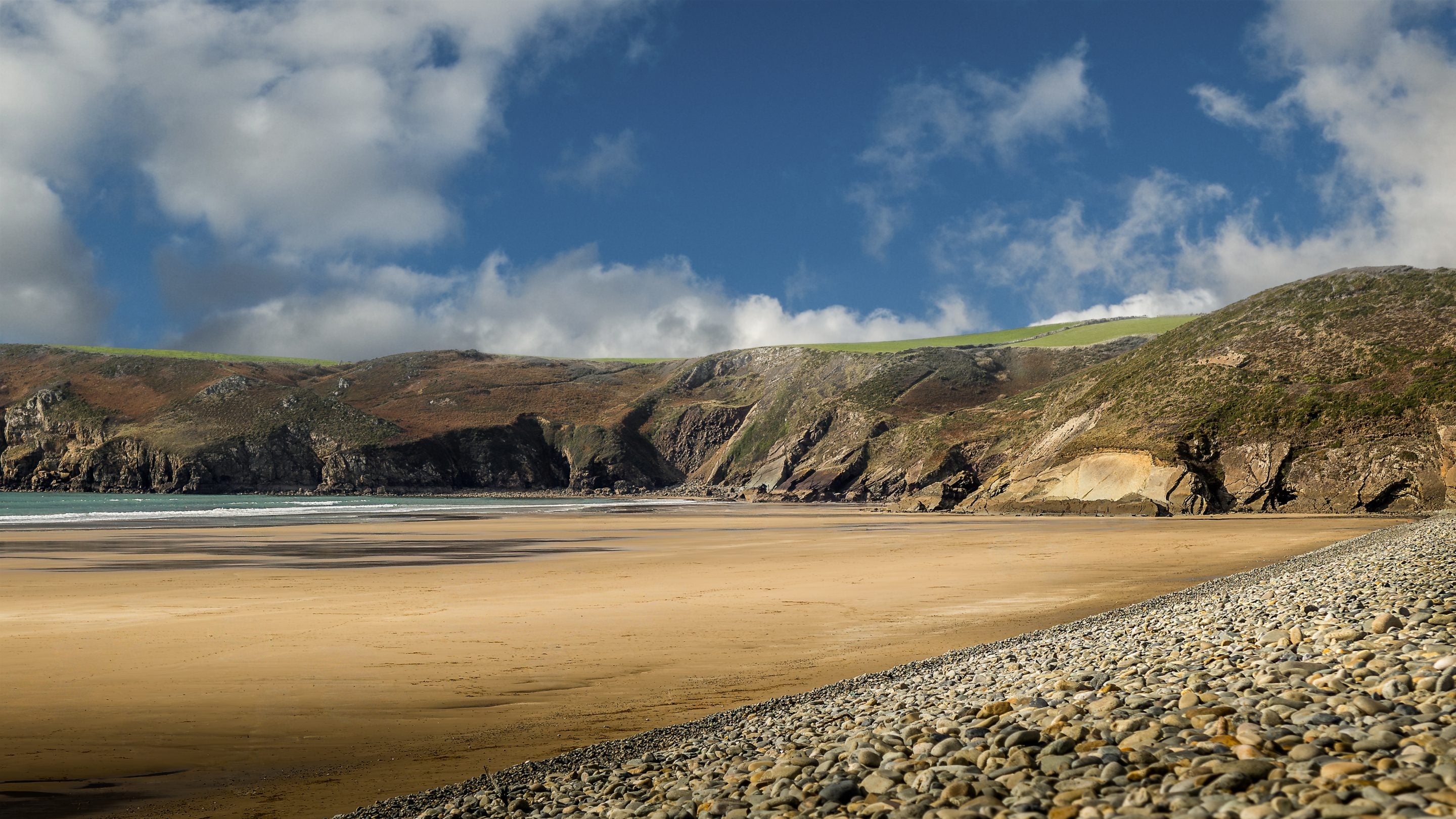 Newgale Beach, showing the pebble bank, golden sand and cliffs surrounding the beach, Pembrokeshire