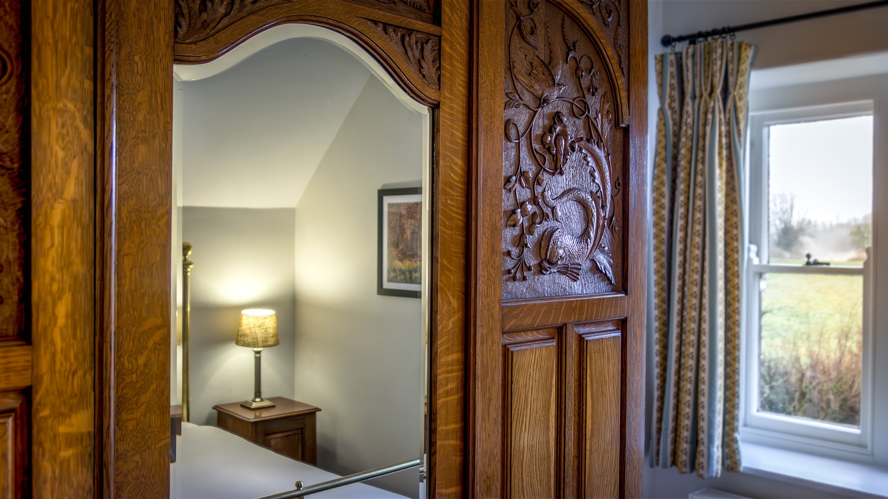 The wooden wardrobe with mirror and carved details in one of the double bedrooms at Penparc, Carmarthenshire