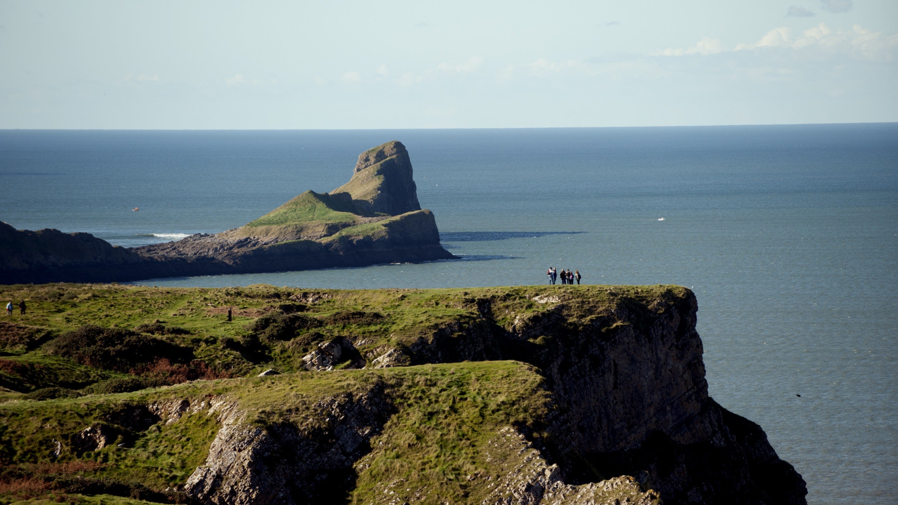 An aerial view of visitors on the cliffs looking towards Worms Head, South Wales