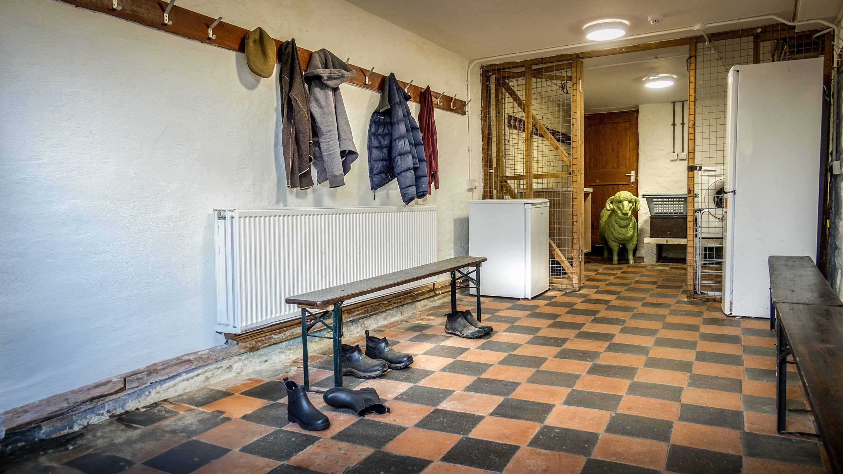 The drying room, with washing machine, benches, and pegs on the wall, at Watkin Bunkhouse, Gwynedd