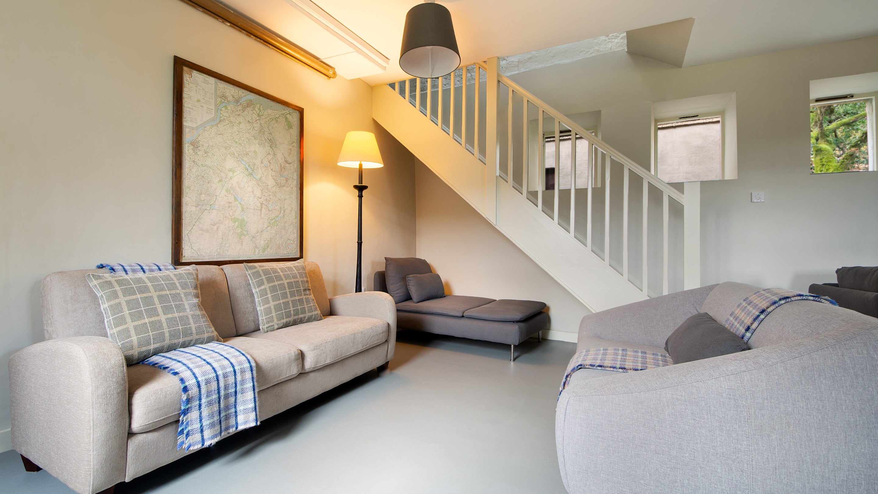 Part of the sitting room at Watkin Bunkhouse, with sofas and the staircase to the first floor, Gwynedd