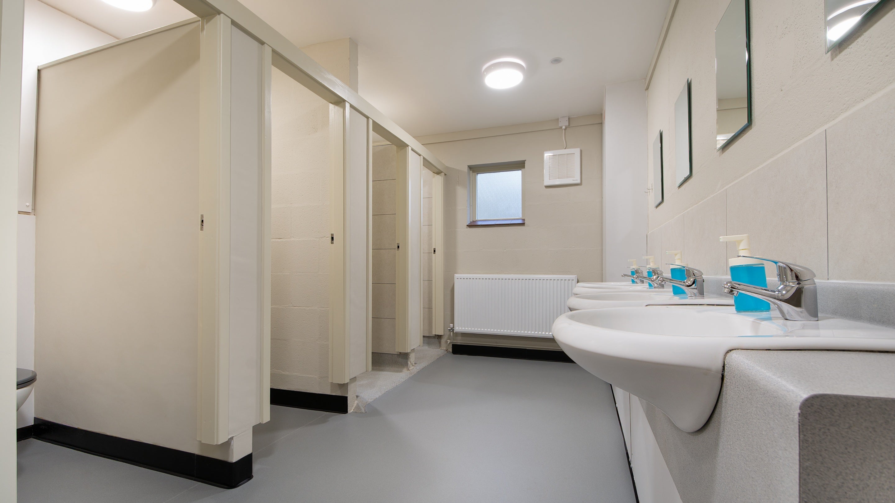 One of the shower rooms on the first floor of Watkin Bunkhouse, with two shower cubicles, two toilet cubicles and sinks, Gwynedd