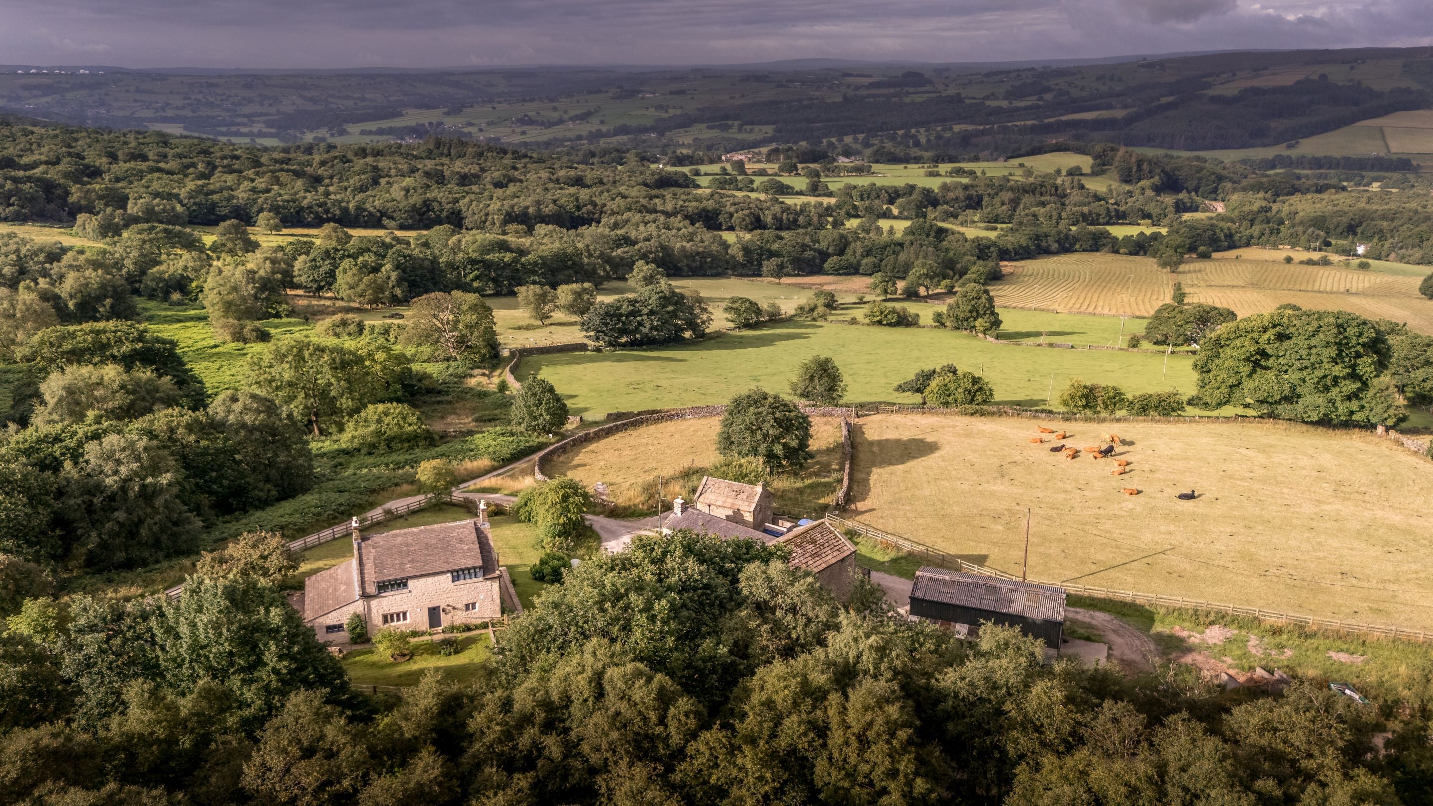 An aerial view of the back of Druid's Cave Farmhouse and the Nidderdale countryside beyond, North Yorkshire