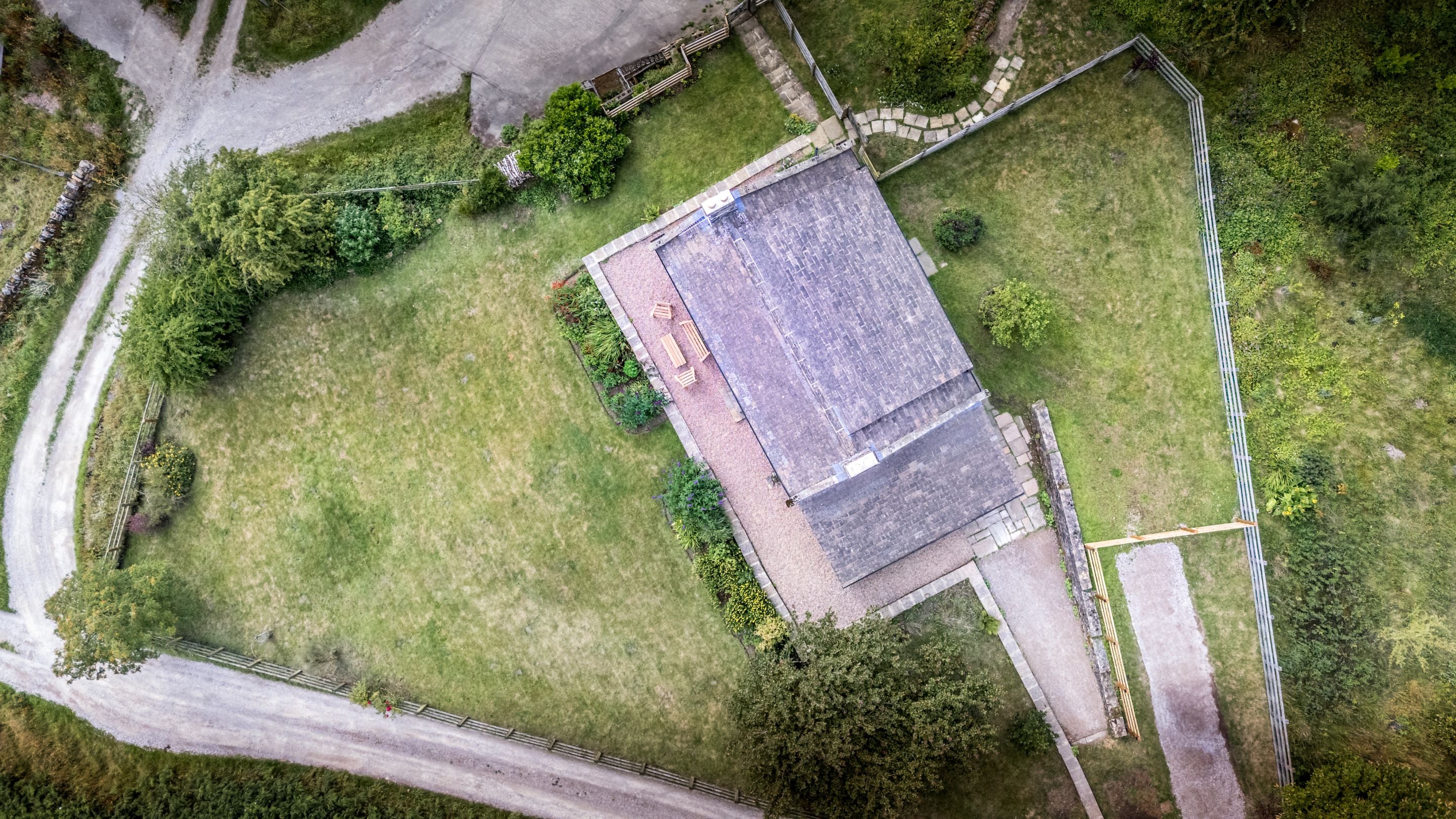 An aerial view over top of Druid's Cave Farmhouse, its large garden, patio and parking area, North Yorkshire