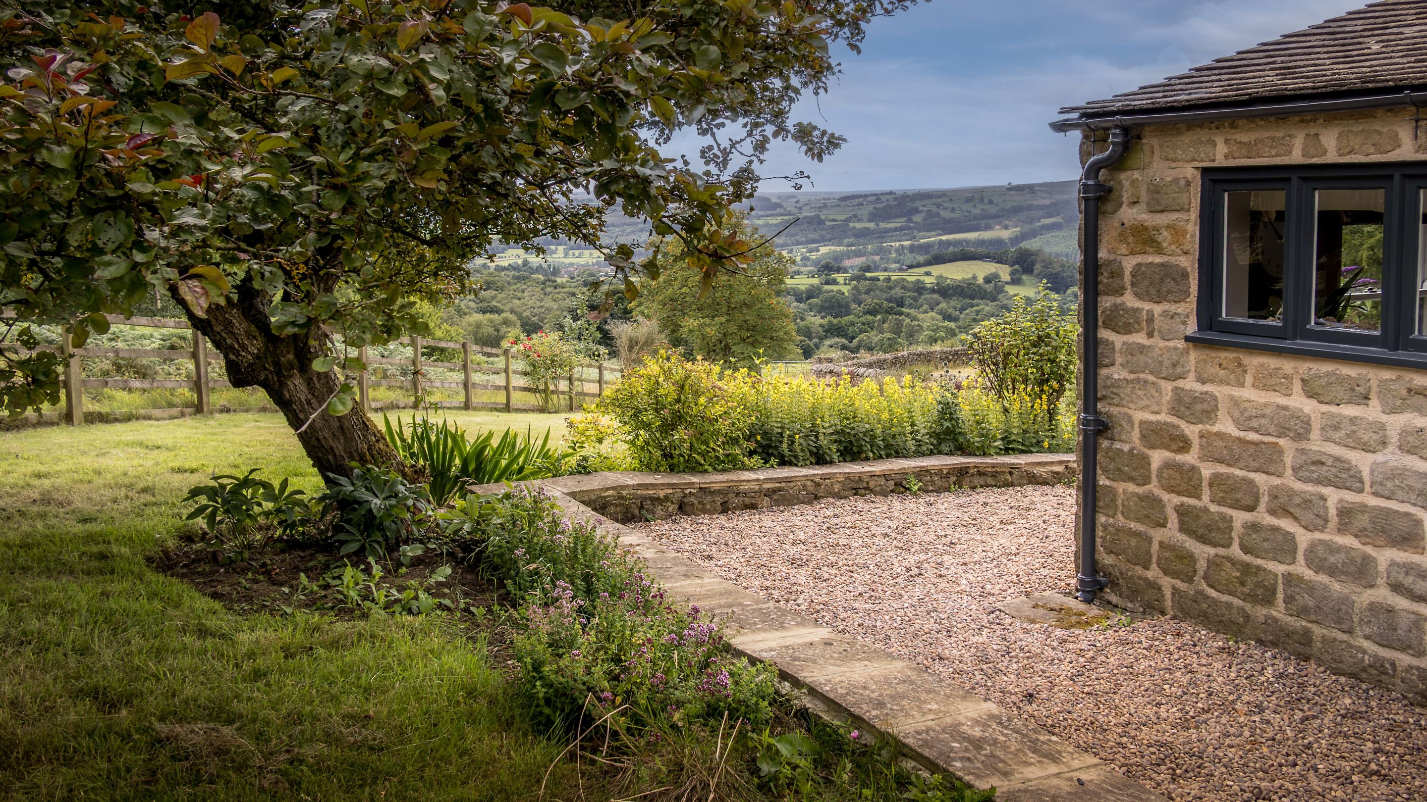 The side of Druid's Cave Farmhouse and part of the garden, overlooking Nidderdale National Landscape, North Yorkshire