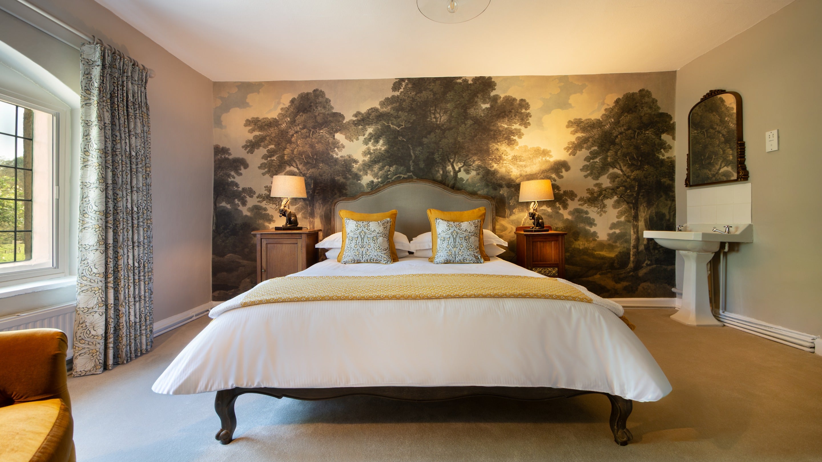 One of the king-size bedrooms on the first floor of Fountains Cottage, with mural wallpaper of a woodland behind the bed, Yorkshire