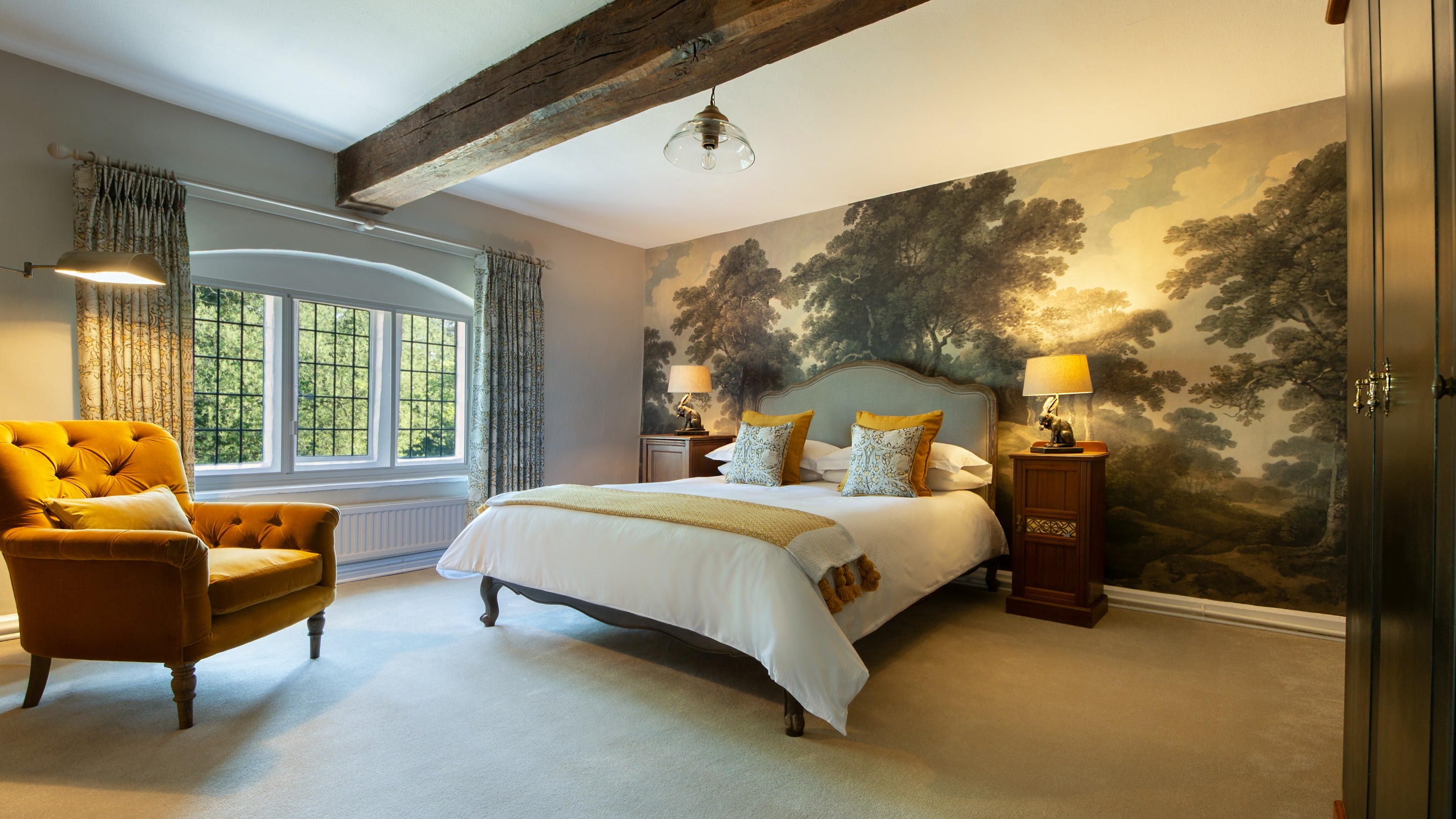 One of the king-size bedrooms on the first floor of Fountains Cottage, with mural wallpaper of a woodland behind the bed, Yorkshire