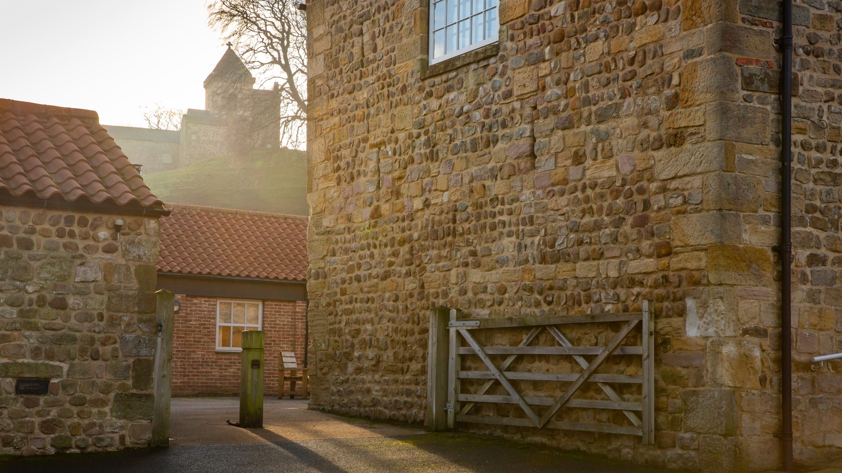 The entrance to the How Hill cottages' courtyard, with the tower at the top of the hill in the distance, Yorkshire