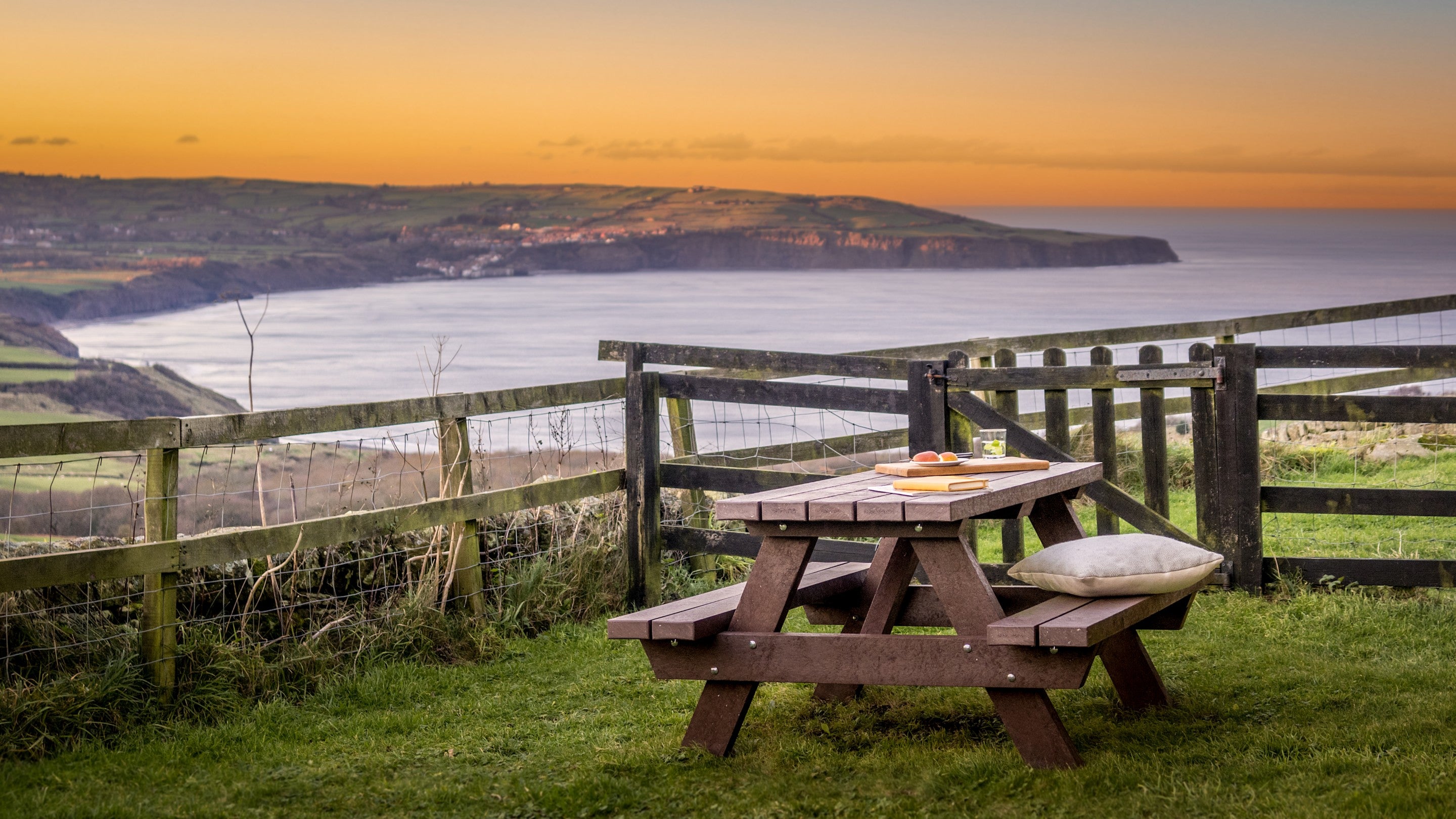 The garden with picnic table and views across the bay at Ravenscar Chapel Cottage, North Yorkshire