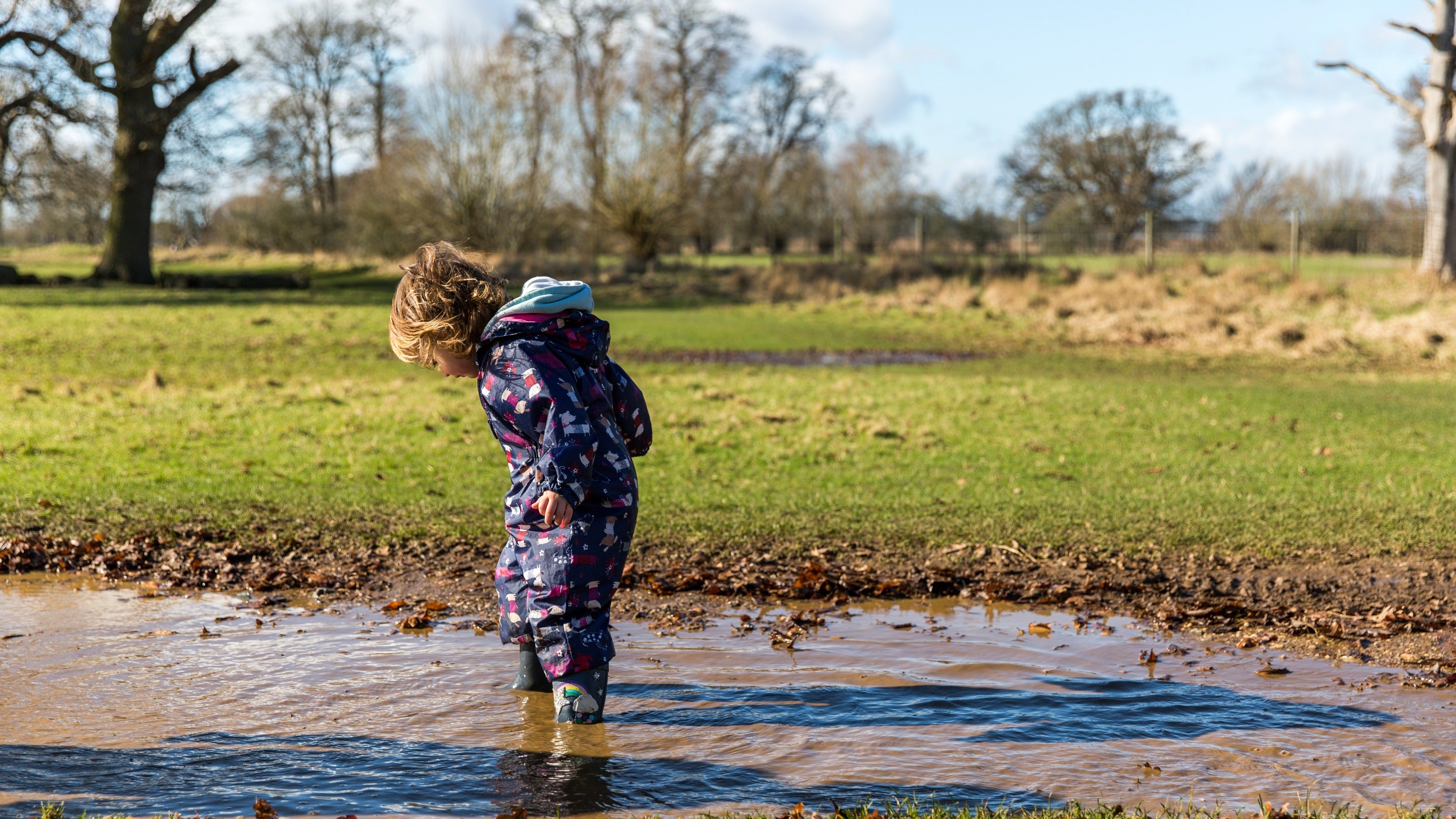 Child splashing in muddy puddles at Charlecote Park, Warwickshire