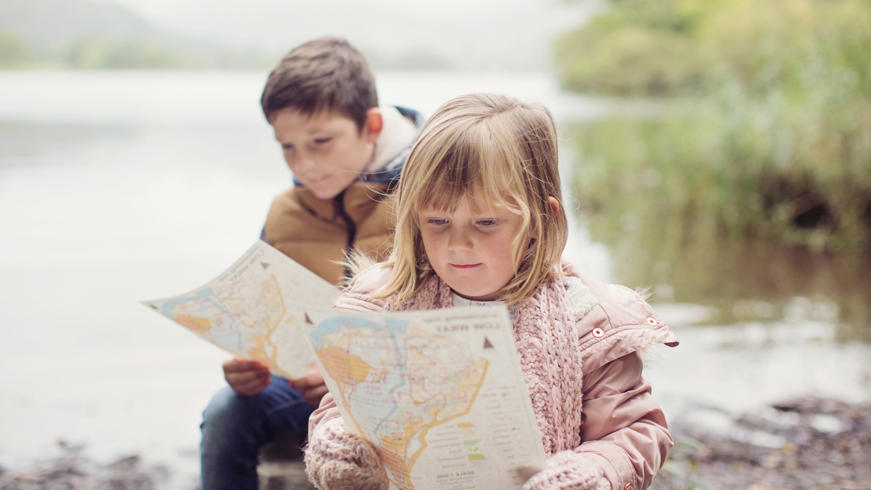Two children looking at maps at Low Wray campsite on the shore of Lake Windermere in the Lake District