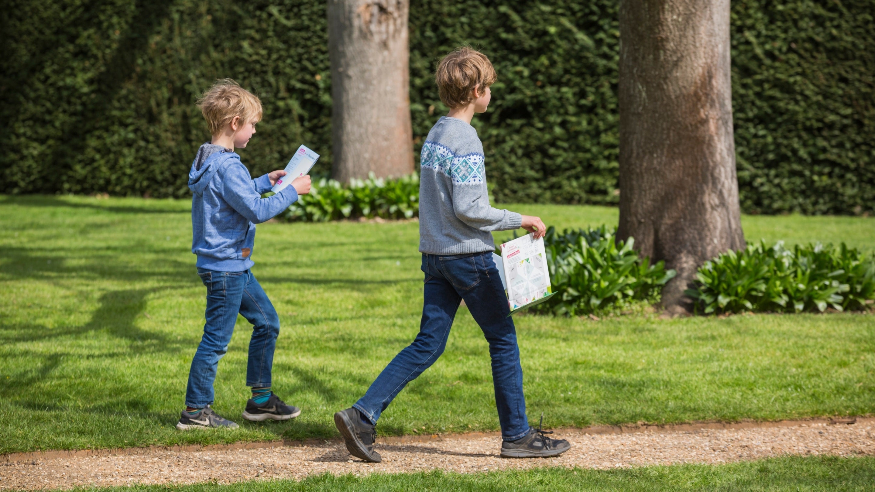 Two children walk along a path doing an Easter trail in the grounds of Osterley Park and House, West London