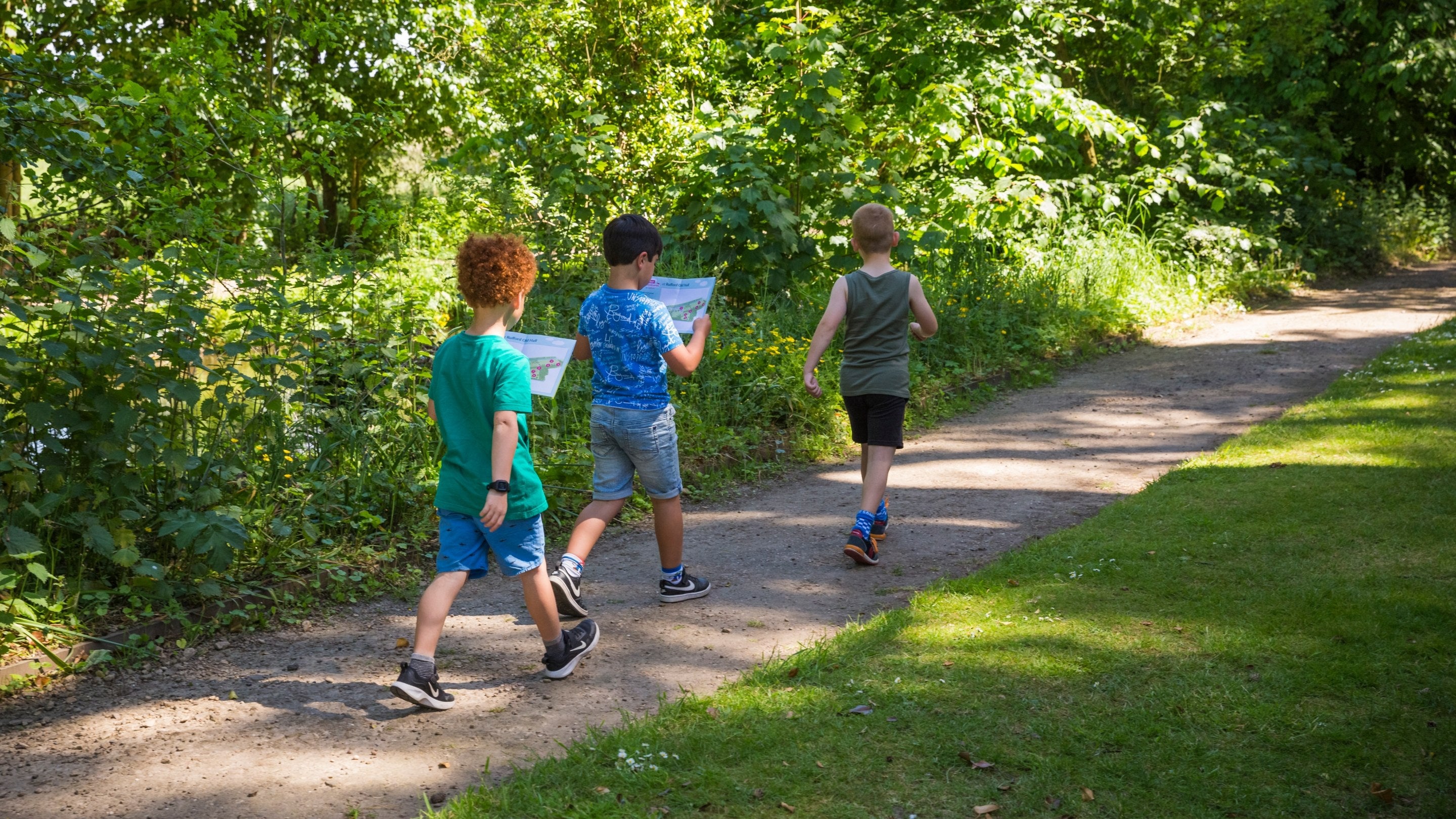 Three children walk along a path doing an Easter activity trail at Rufford Old Hall Lancashire