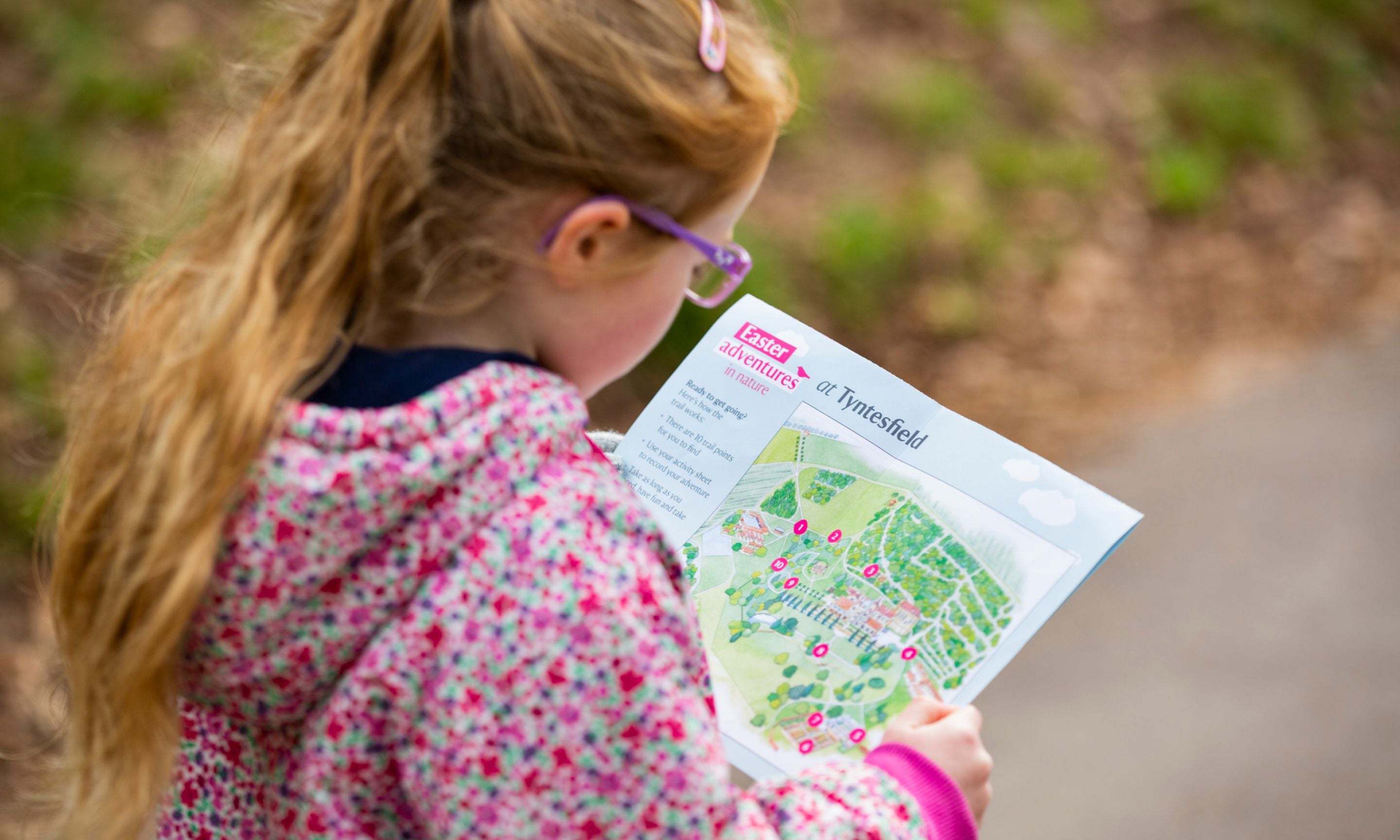 Girl looking at activity sheet on the Easter trail at Tyntesfield, Somerset