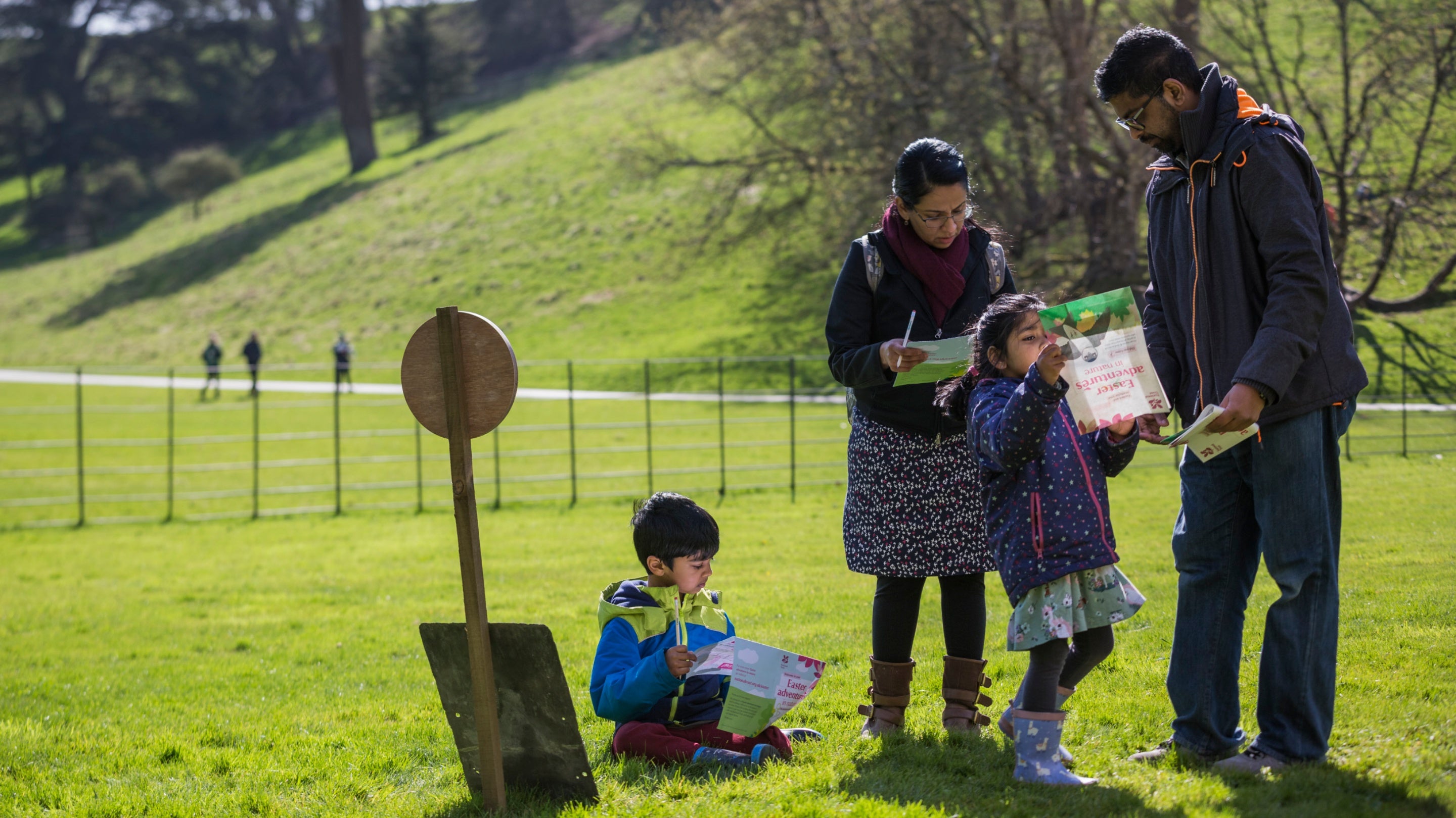 Parents with two children looking at trail sheets in parkland