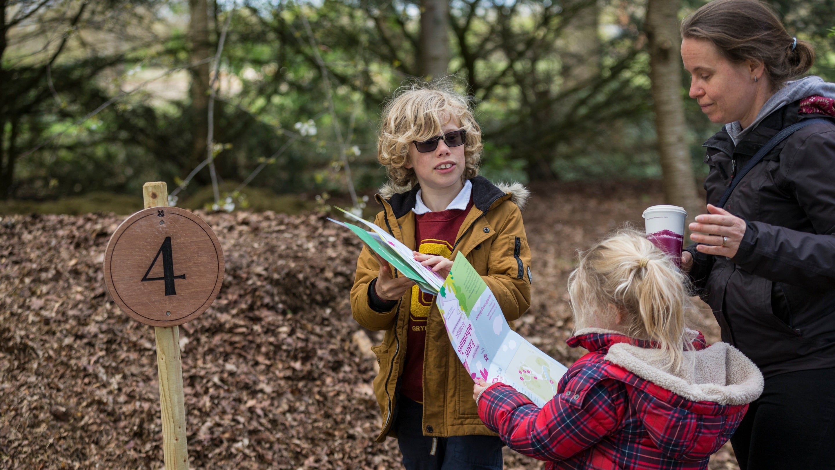 An adult and two children doing the Easter activity trail in the woodland at Osterley Park and House, West London