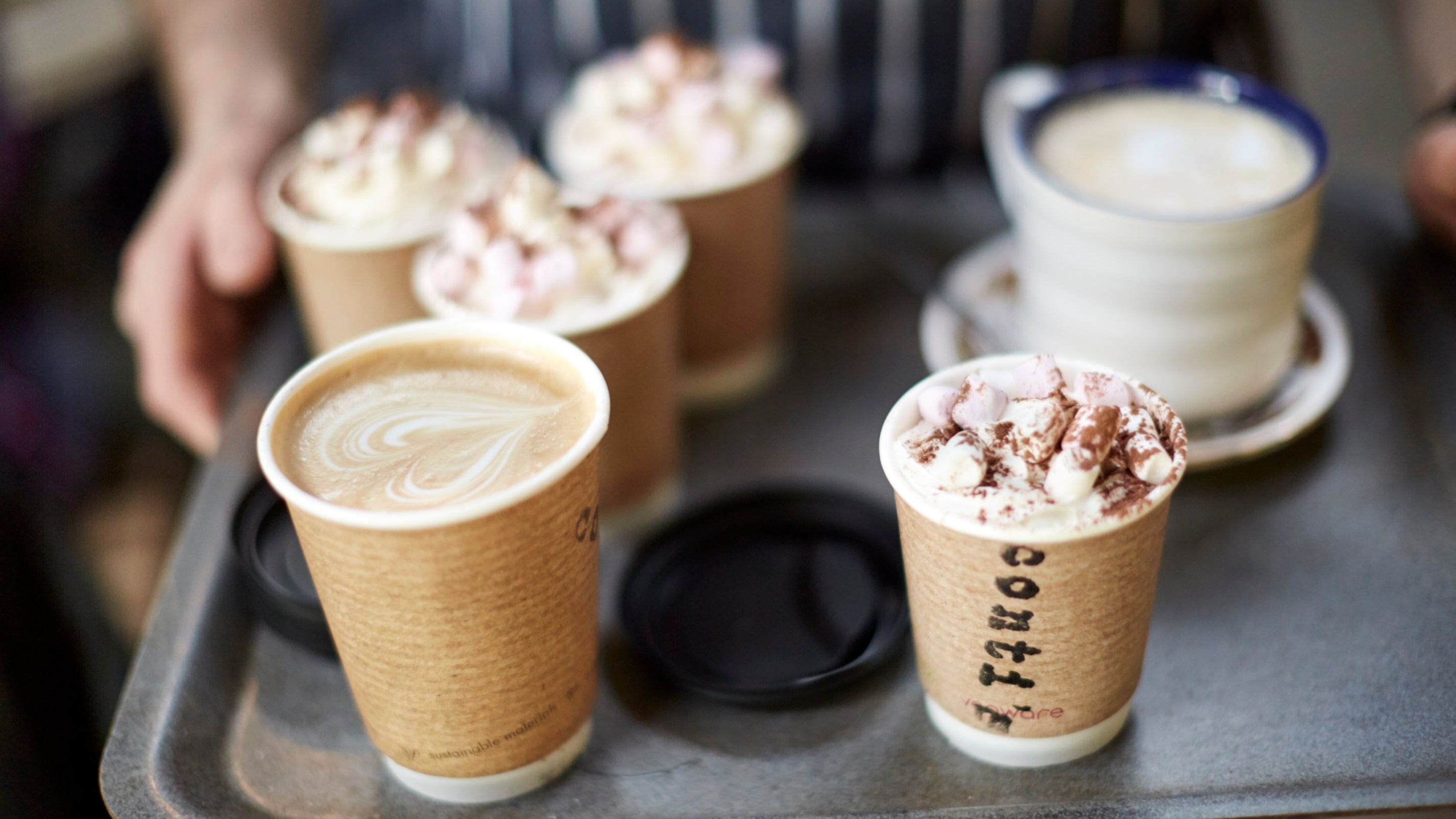 Catering assistant with a tray of coffee and hot chocolate in the cafe at Llanerchaeron, Wales.