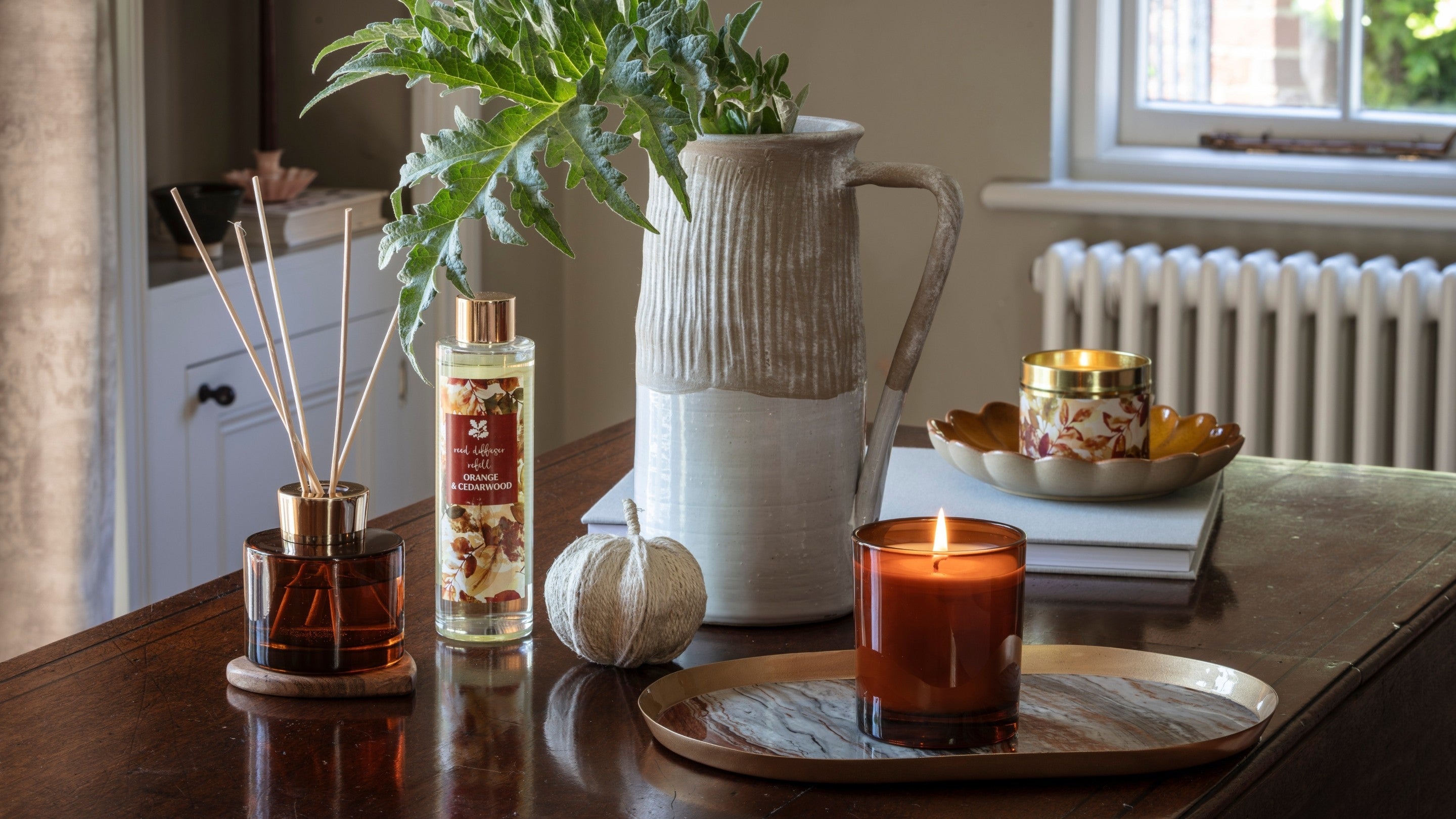 A candle, reed diffuser and jug on a table