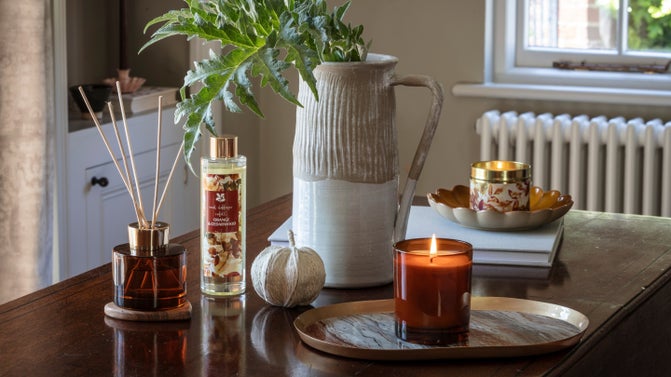 A candle, reed diffuser and jug on a table