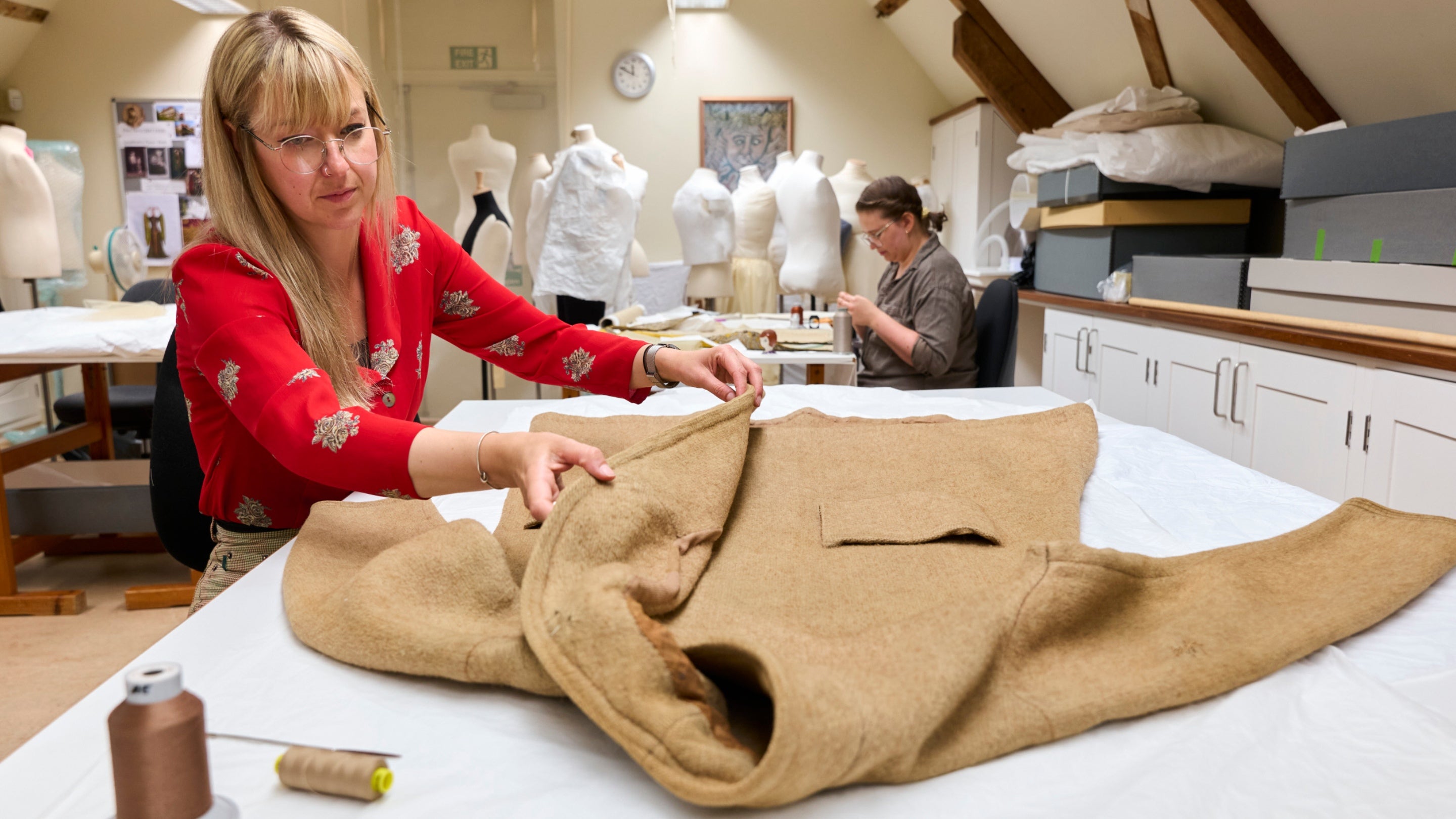 Person laying out a coat that belonged to Thomas Carlyle to be conserved