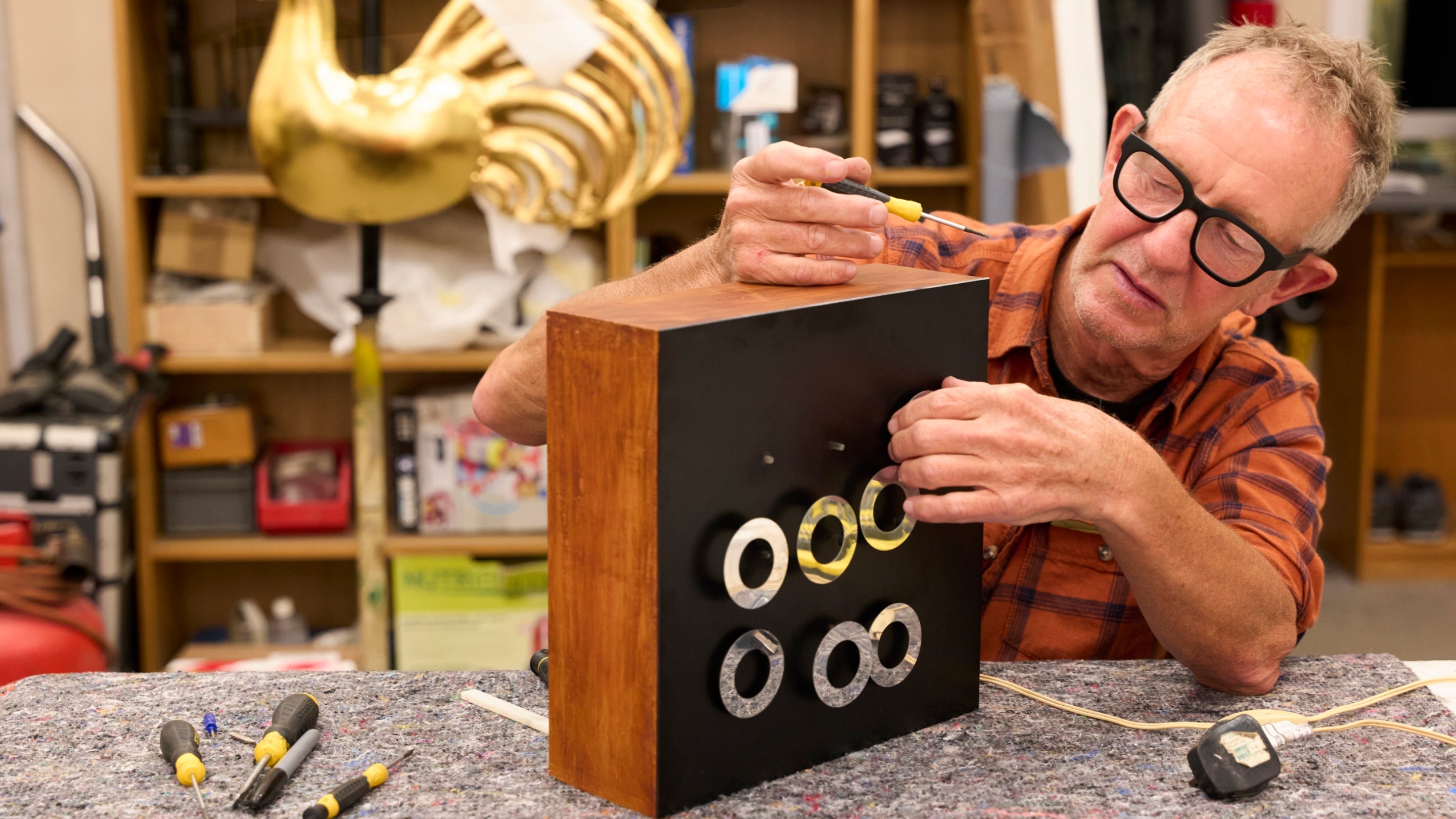 A person fixing a work of art that is several metal rings