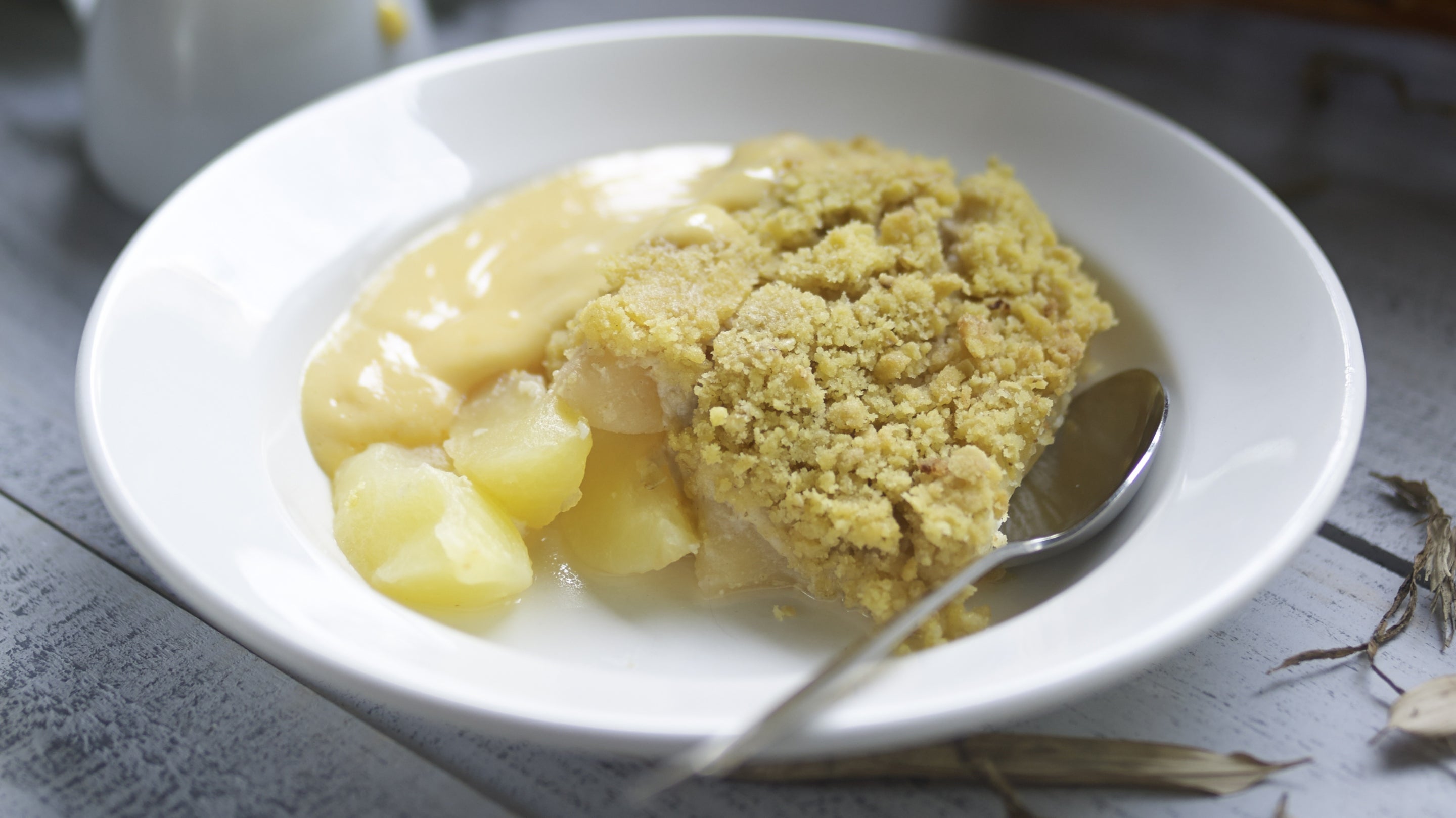 Baked apple crumble in a bowl with a spoon on the bowl