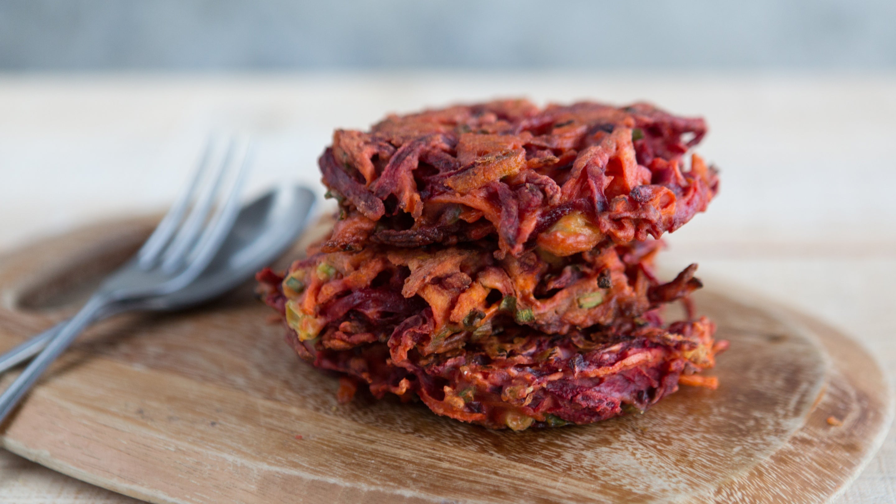 Stack of cooked beetroot fritters on a chopping board