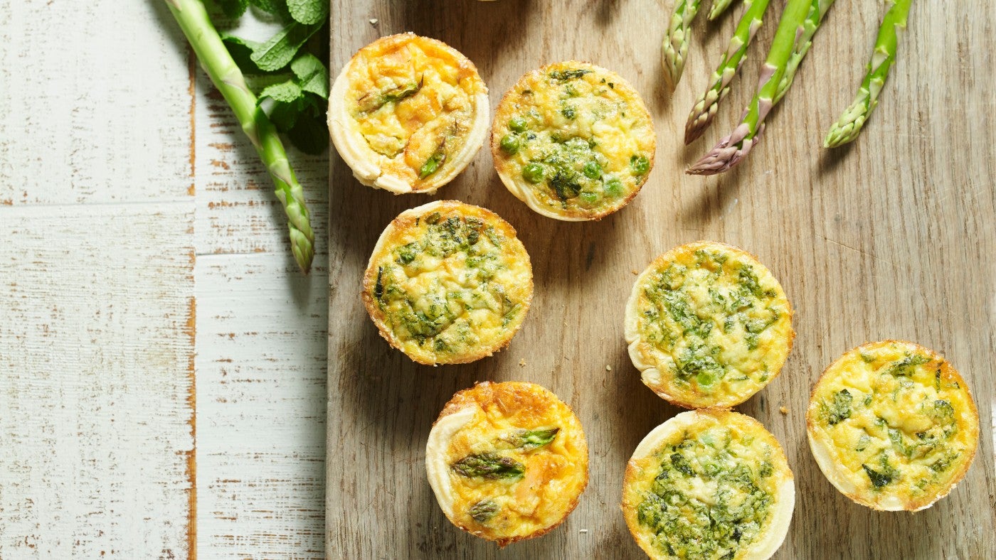 Cooked mini quiches on a wooden chopping board