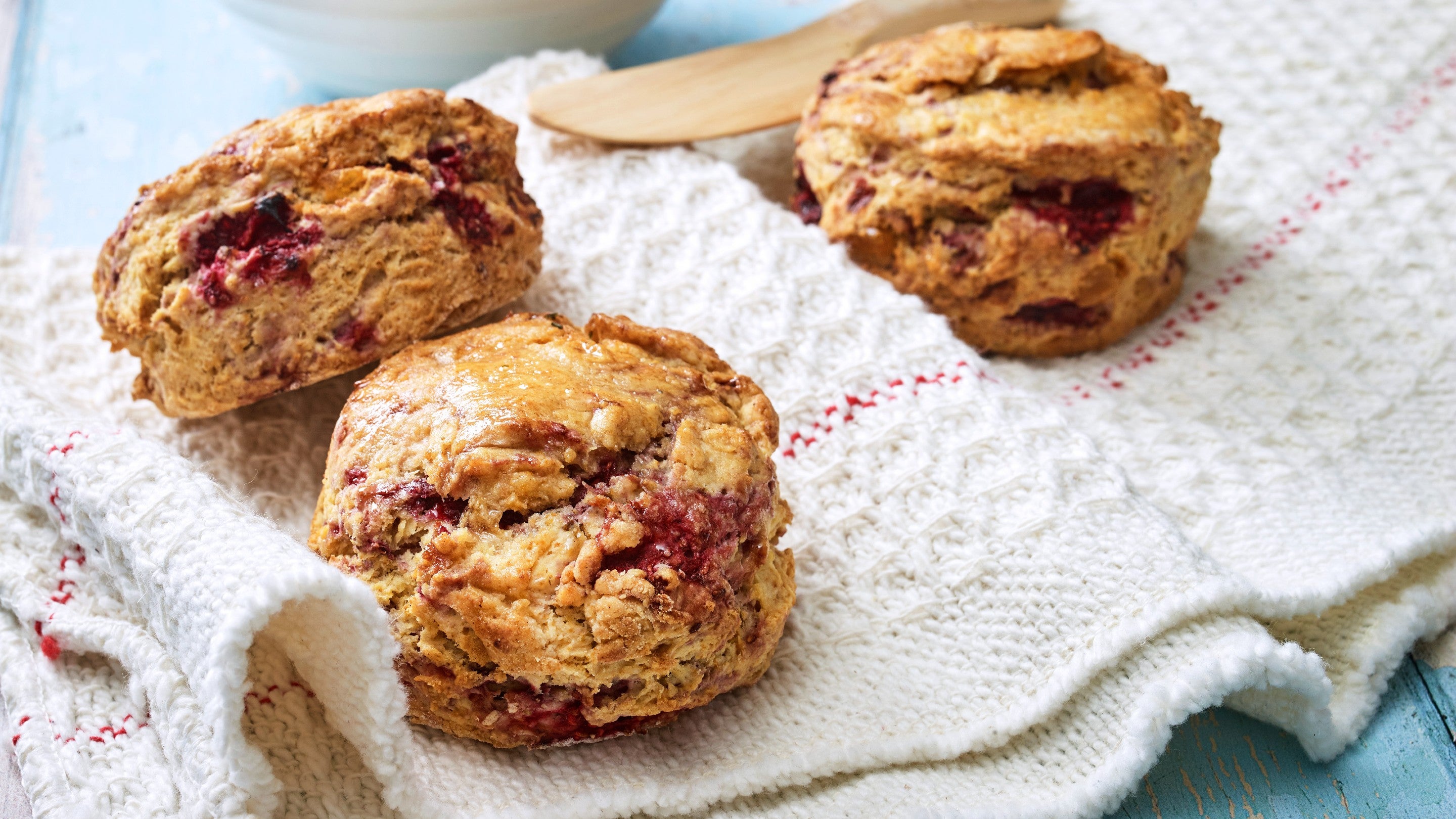 Three cooked raspberry and ginger scones sat on a white tea towel