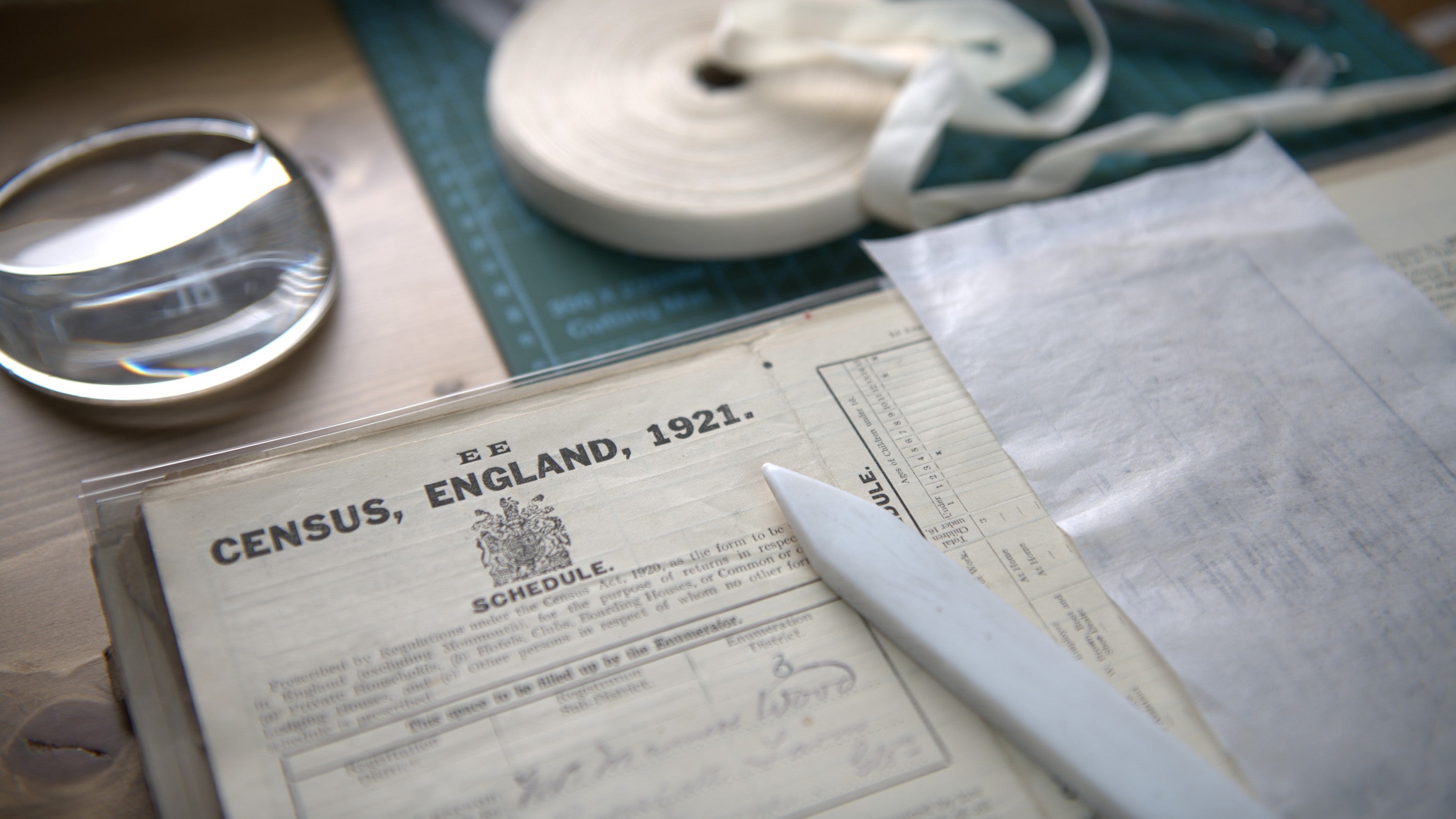 1921 Census records for England on a wooden table with some conservation tools including a magnifying glass