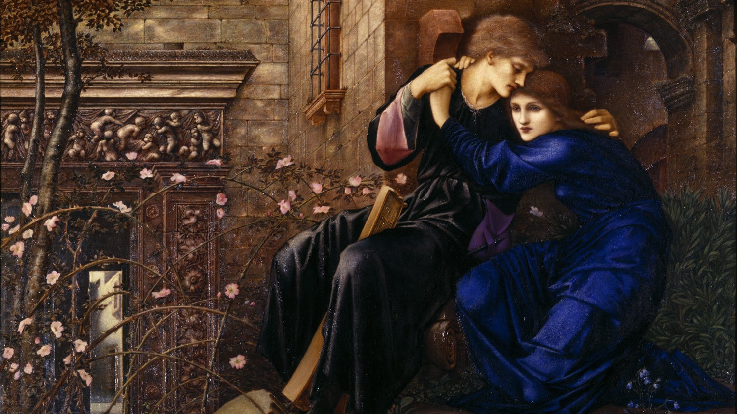 An oil painting depicting a a young couple sat on a stone plinth with their arms around each other. The man wears a black velvet tunic while the woman wears a long blue dress. They are surrounded by ornate architecture with creeping plants with small pink flowers growing all over them.