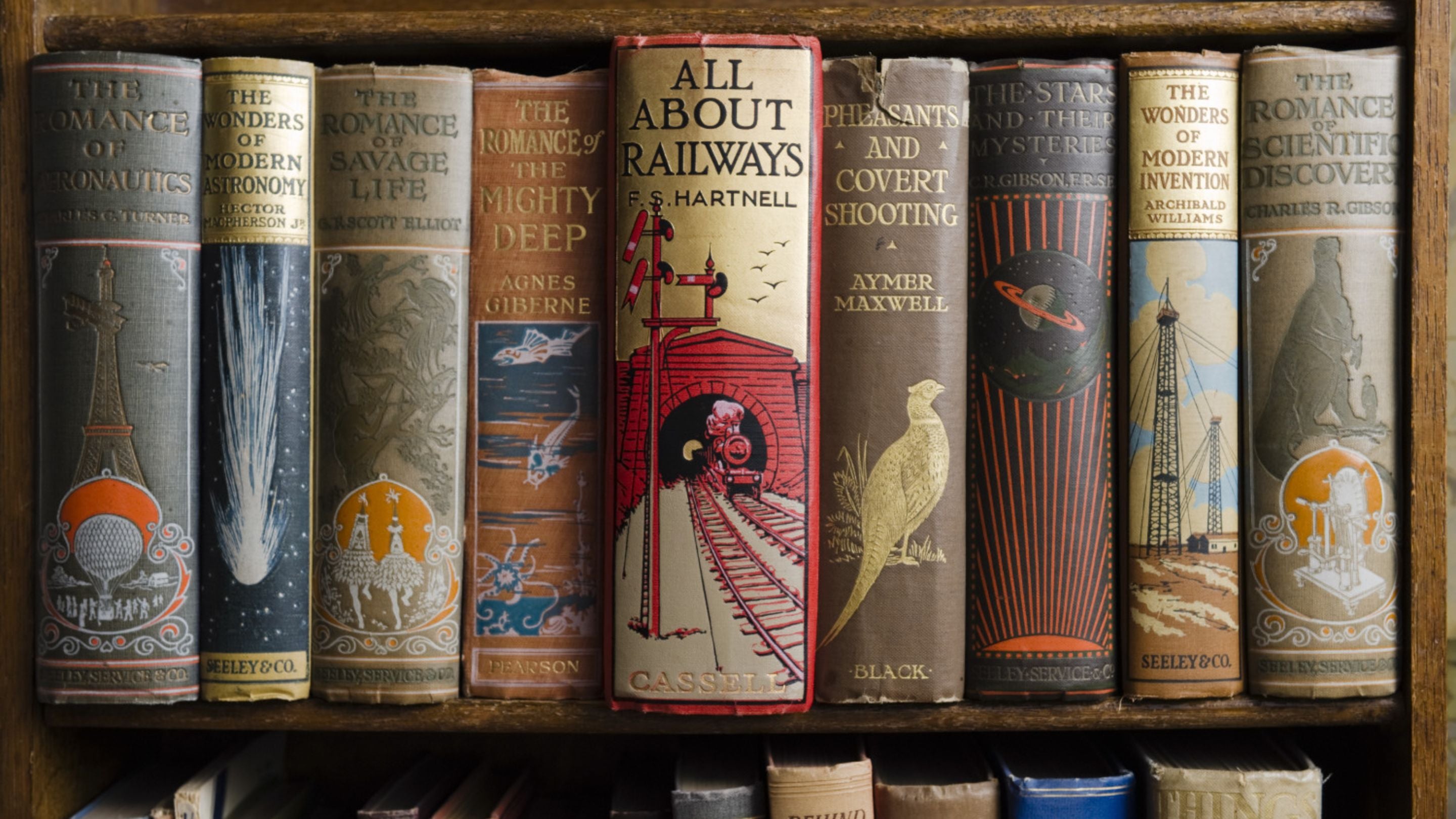 Books on the shelves in the State Bedroom, reflecting the interests of the Bankes family including titles such as The Wonders of Modern Invention and All About Railways, at Kingston Lacy, Dorset.